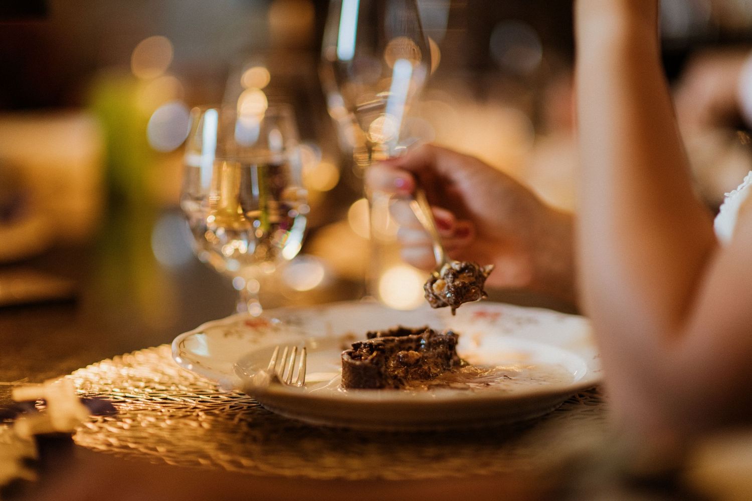 Close-up of elegant wedding reception dinner plate with food and champagne glass being raised.