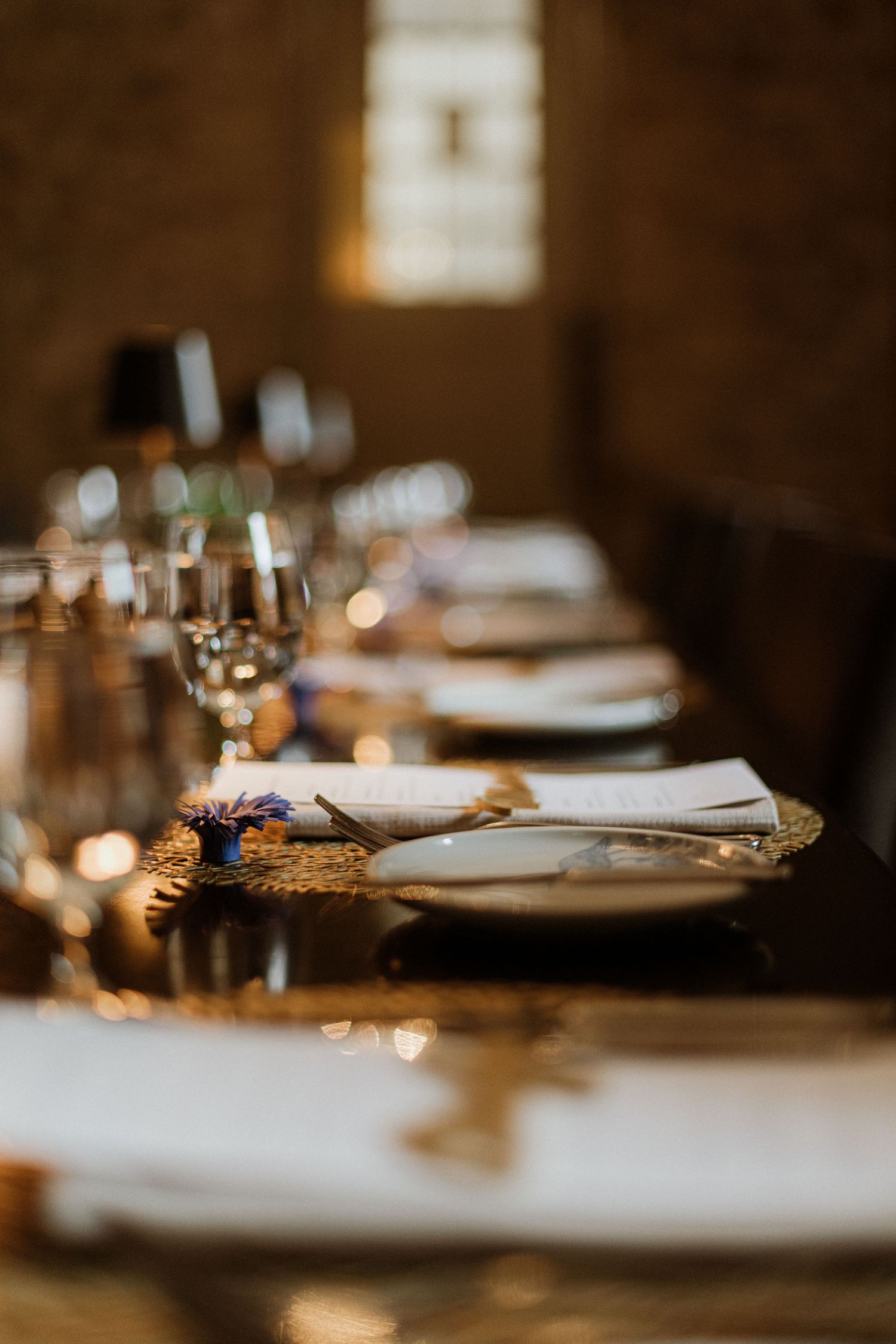 Close-up of elegant wedding reception place setting with gold charger plate and linen napkin.