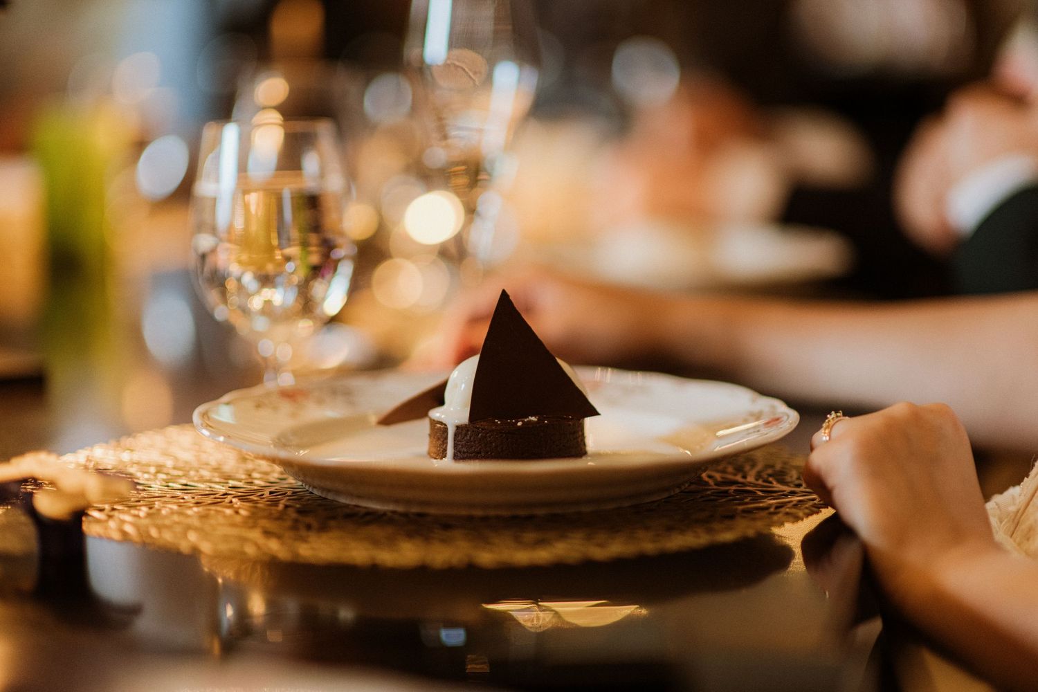 Elegant wedding reception place setting with folded dark napkin on white plate with gold charger.