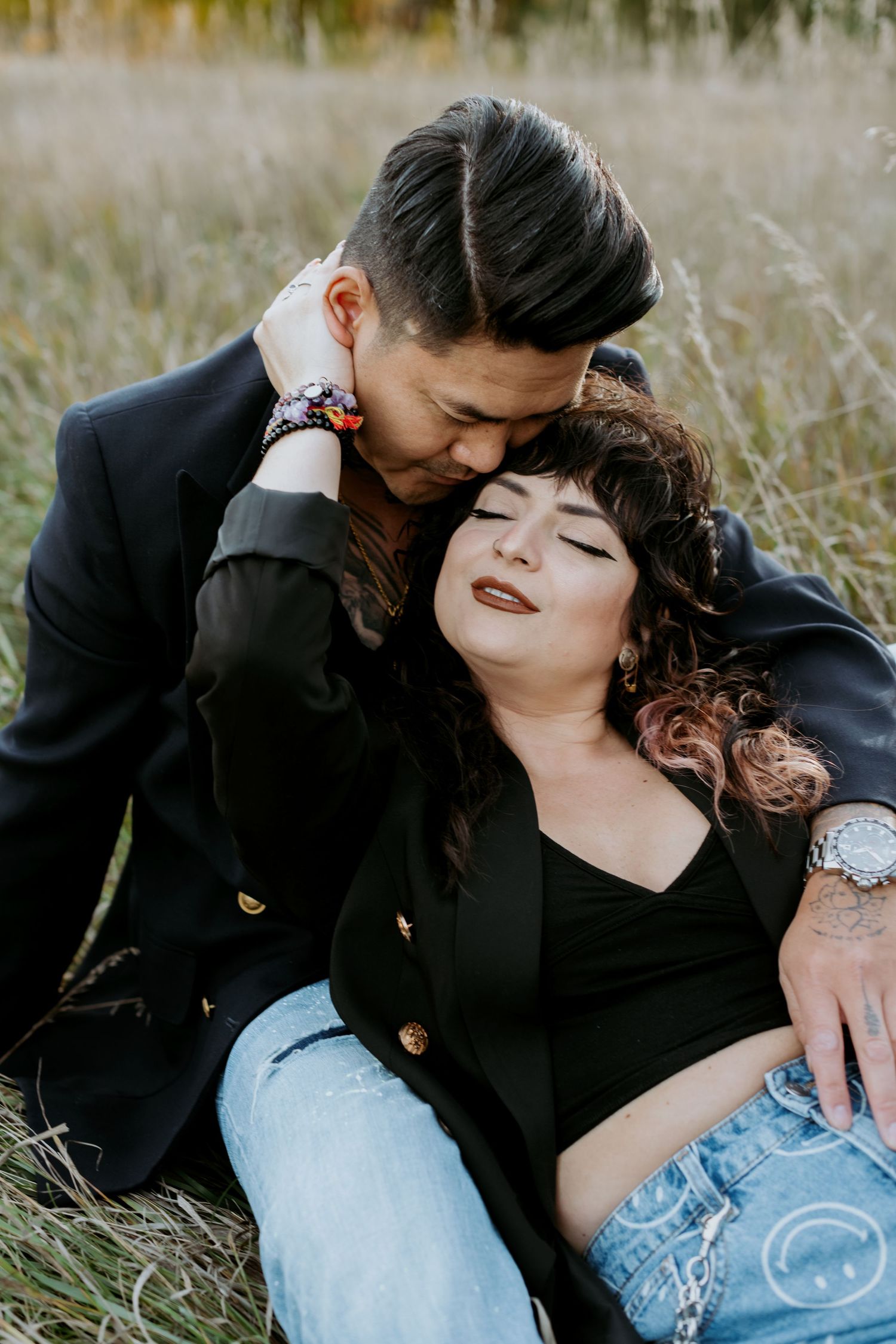 Man kissing womans head while she leans back in a golden grass field.