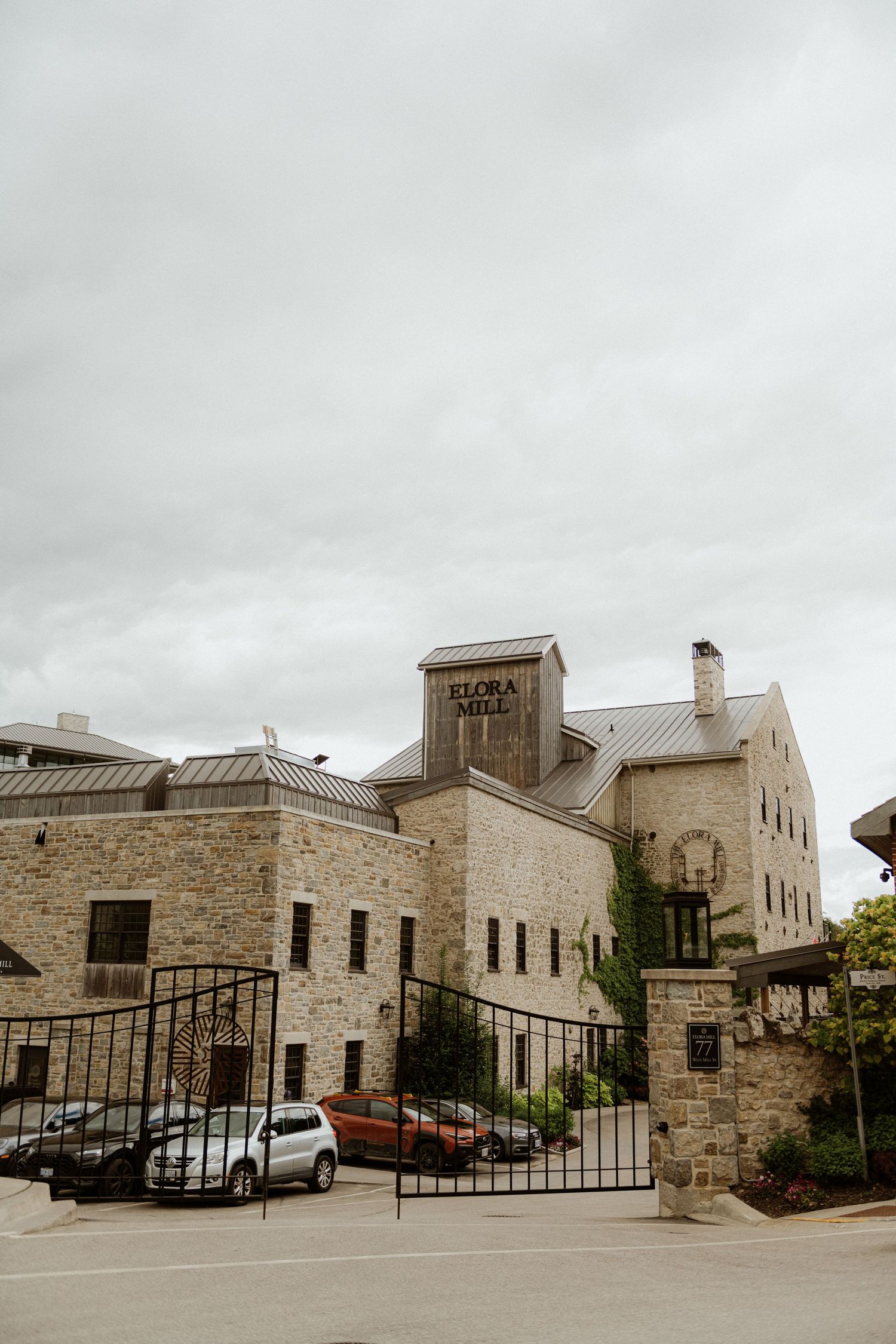 Elora Mill historic stone building entrance with iron gates and ivy-covered walls on overcast day.