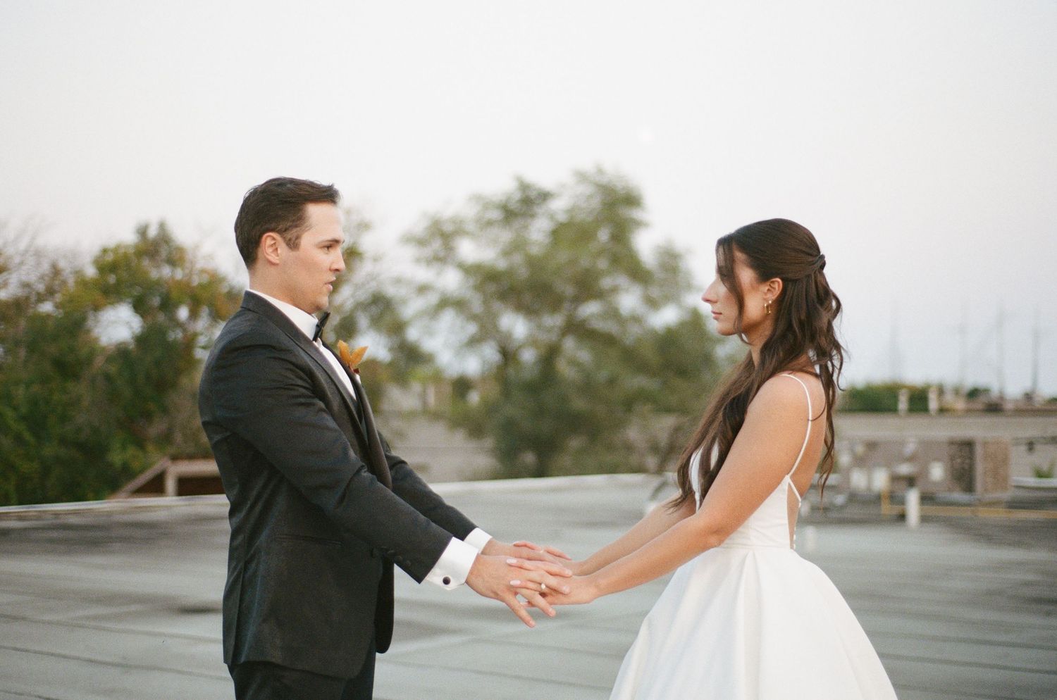 Bride and groom hold hands facing each other in an intimate moment on rooftop wedding venue.