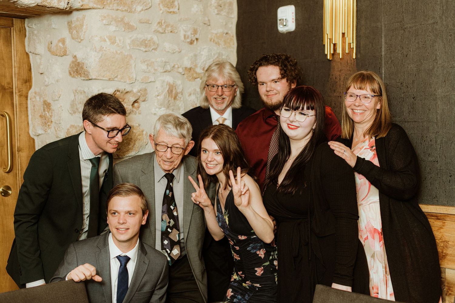 Group of eight wedding guests pose together for fun photo at reception venue.