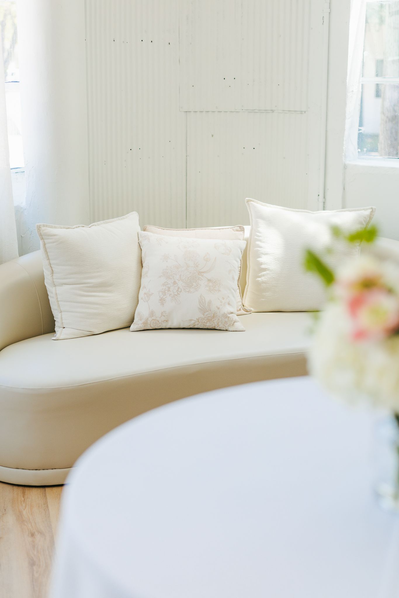 Elegant curved cream sofa with decorative pillows in a bright minimalist white interior.