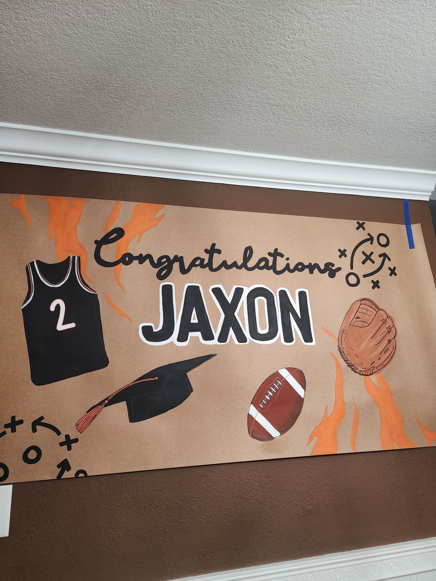 Handmade congratulations banner for Jaxon featuring sports themed decorations including football, baseball glove, and jersey.