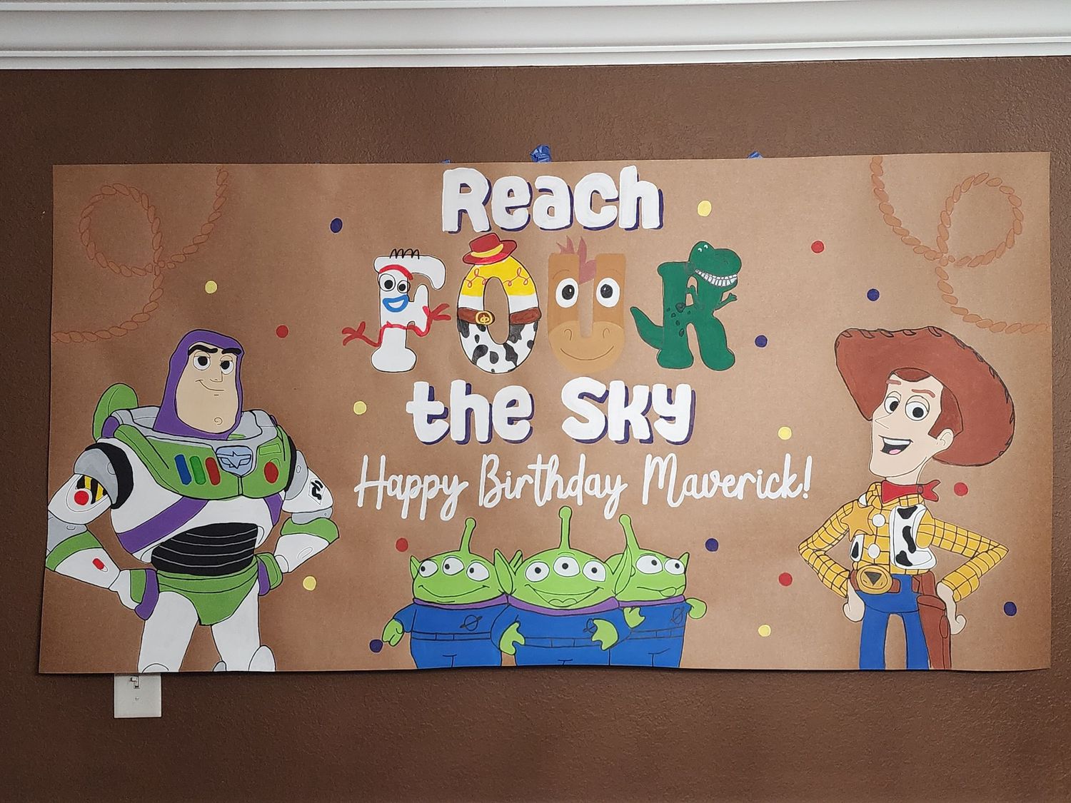 Toy Story themed birthday banner reading Reach for the Sky Happy Birthday Maverick with Buzz Lightyear Woody and aliens.