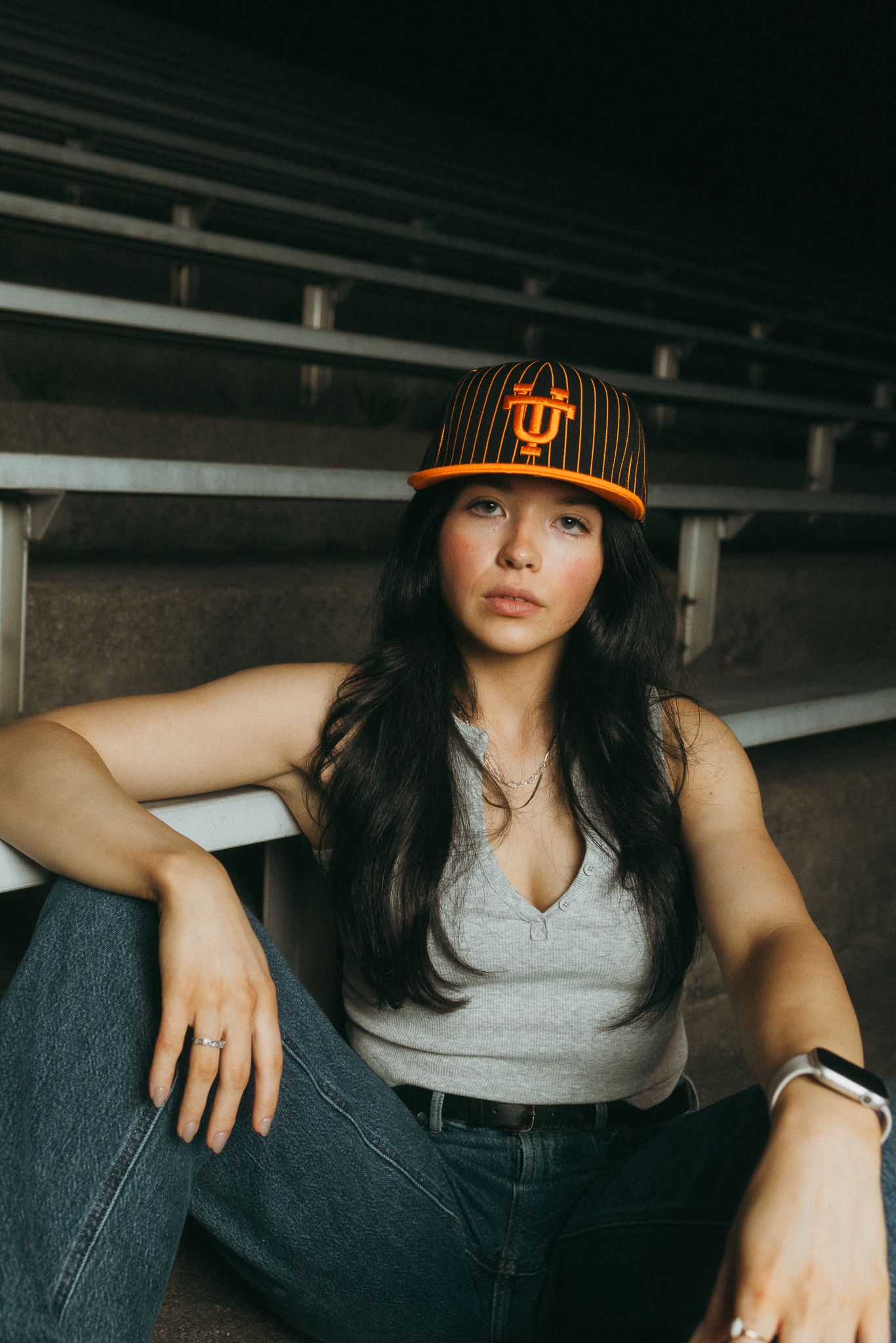 Young woman wearing an orange Tennessee Volunteers pinstripe fitted cap in stadium bleachers.