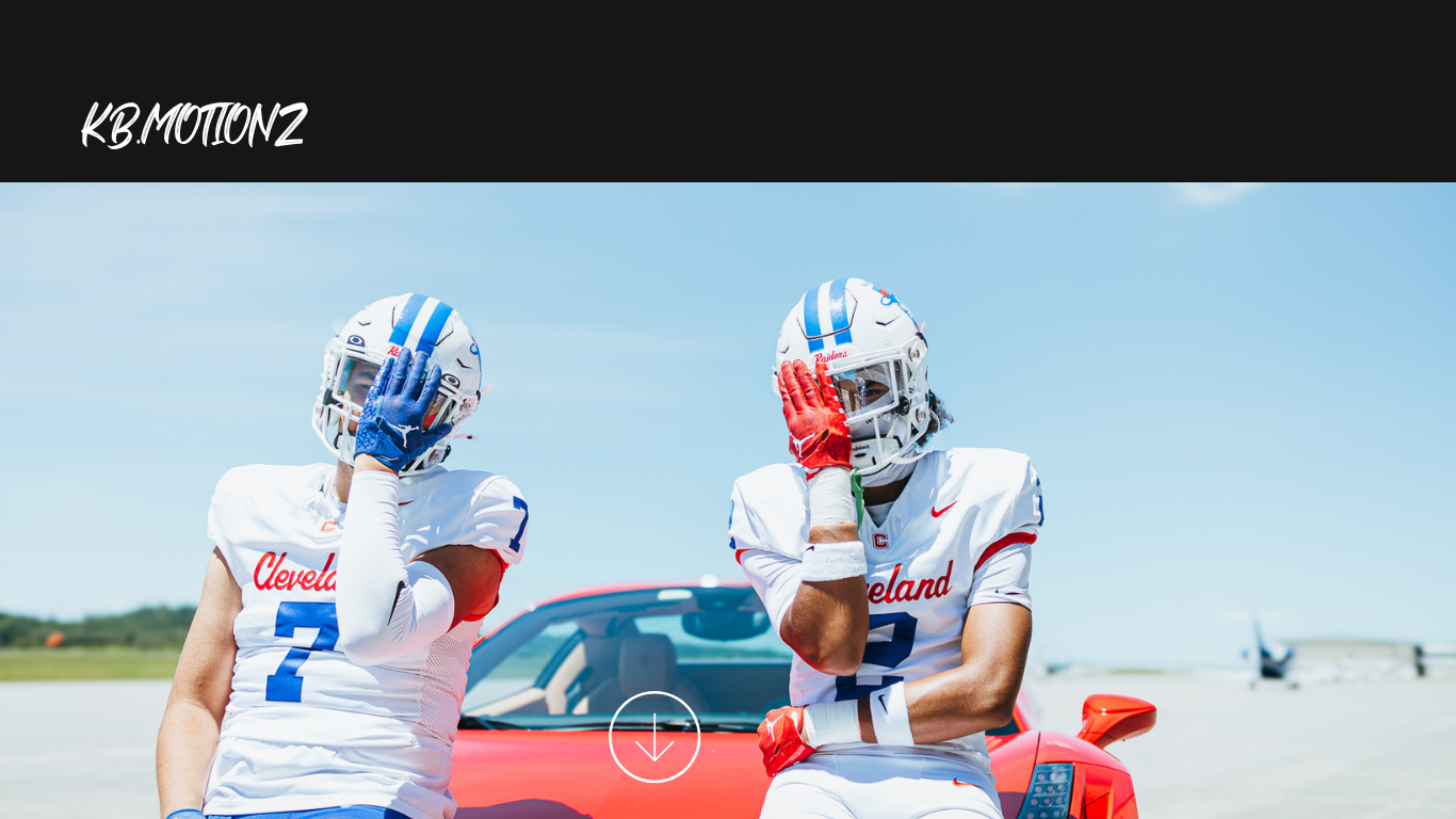 Two football players in blue and white uniforms lean against a red sports car on a runway.