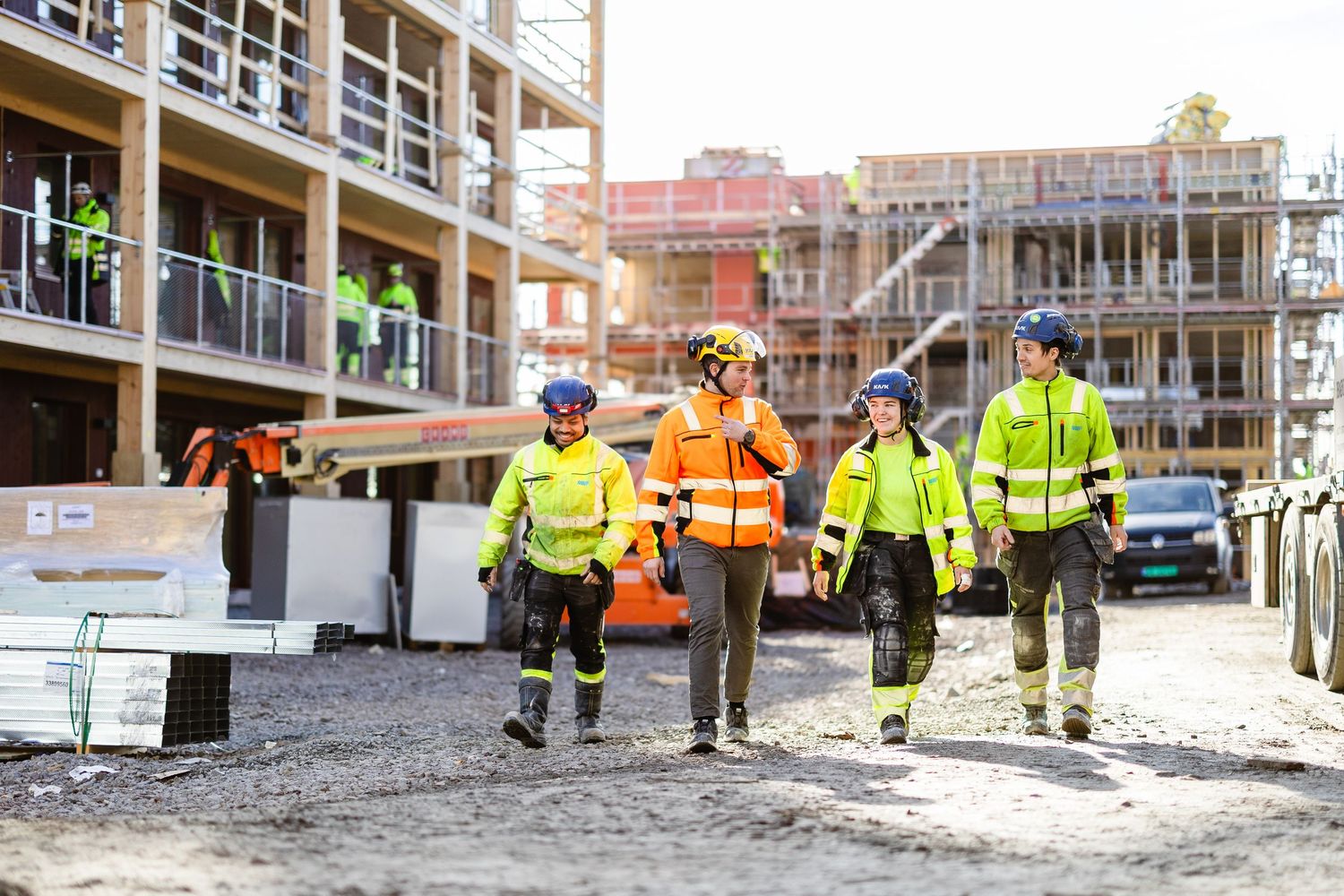 Group of construction workers in high-visibility gear walking through an active building construction site.