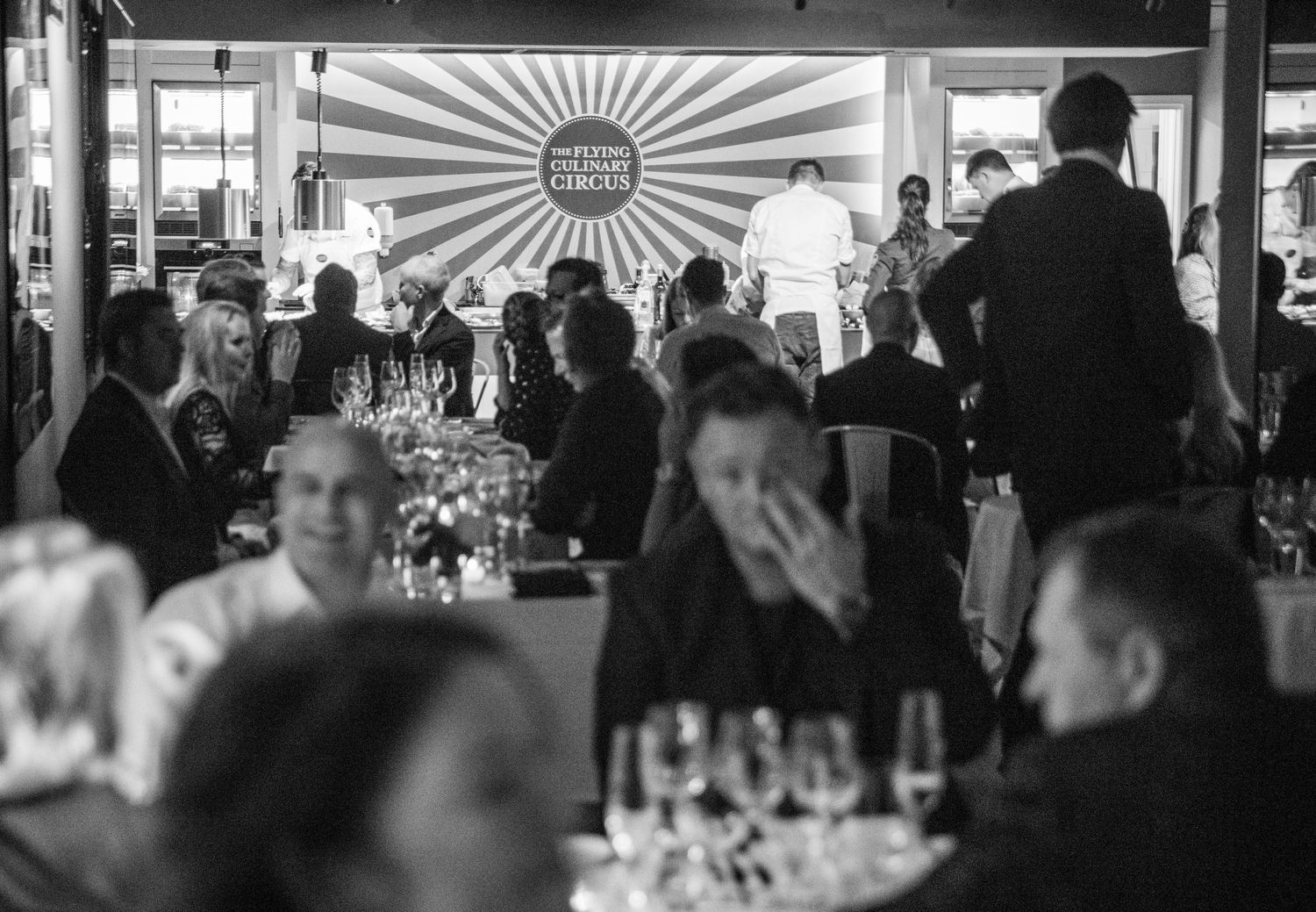 Elegant dinner guests seated at tables during a Flying Culinary Circus gourmet dining experience.