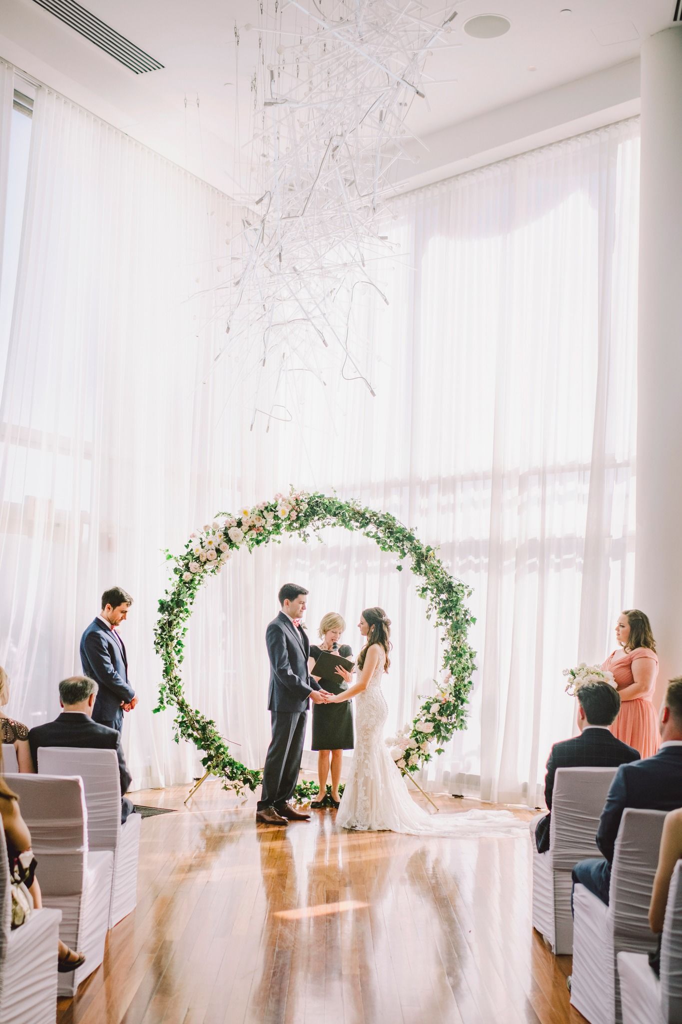 Wedding ceremony setup in modern white room with floral arches and rows of chairs for guests at Sequoia Restaurant in Washington DC.