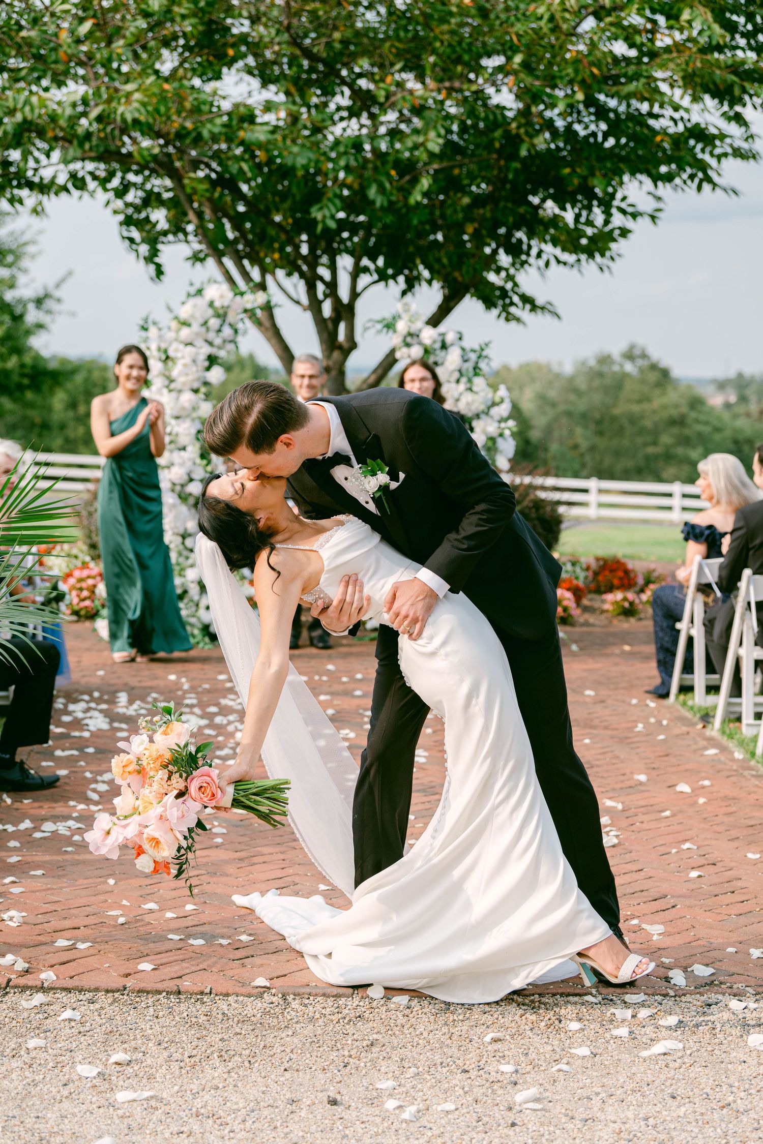 A photo of a couple performing a dip dance move at their wedding celebration on a petal-covered path during a Belmont Country Club wedding.