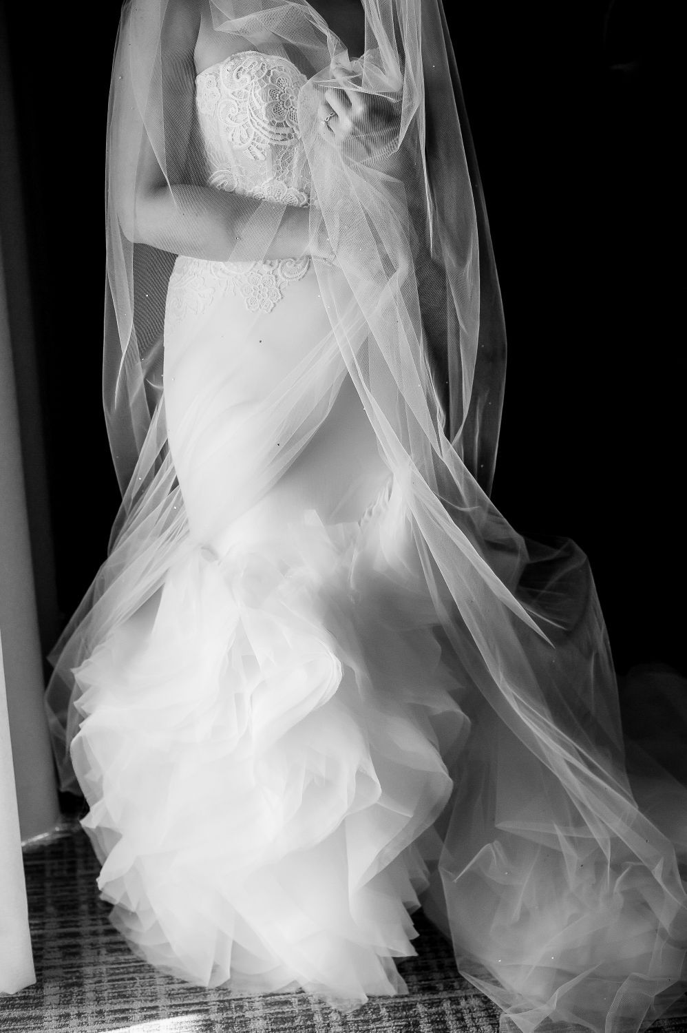 Close-up view of a white wedding dress showing intricate ruffles and layers of tulle fabric.