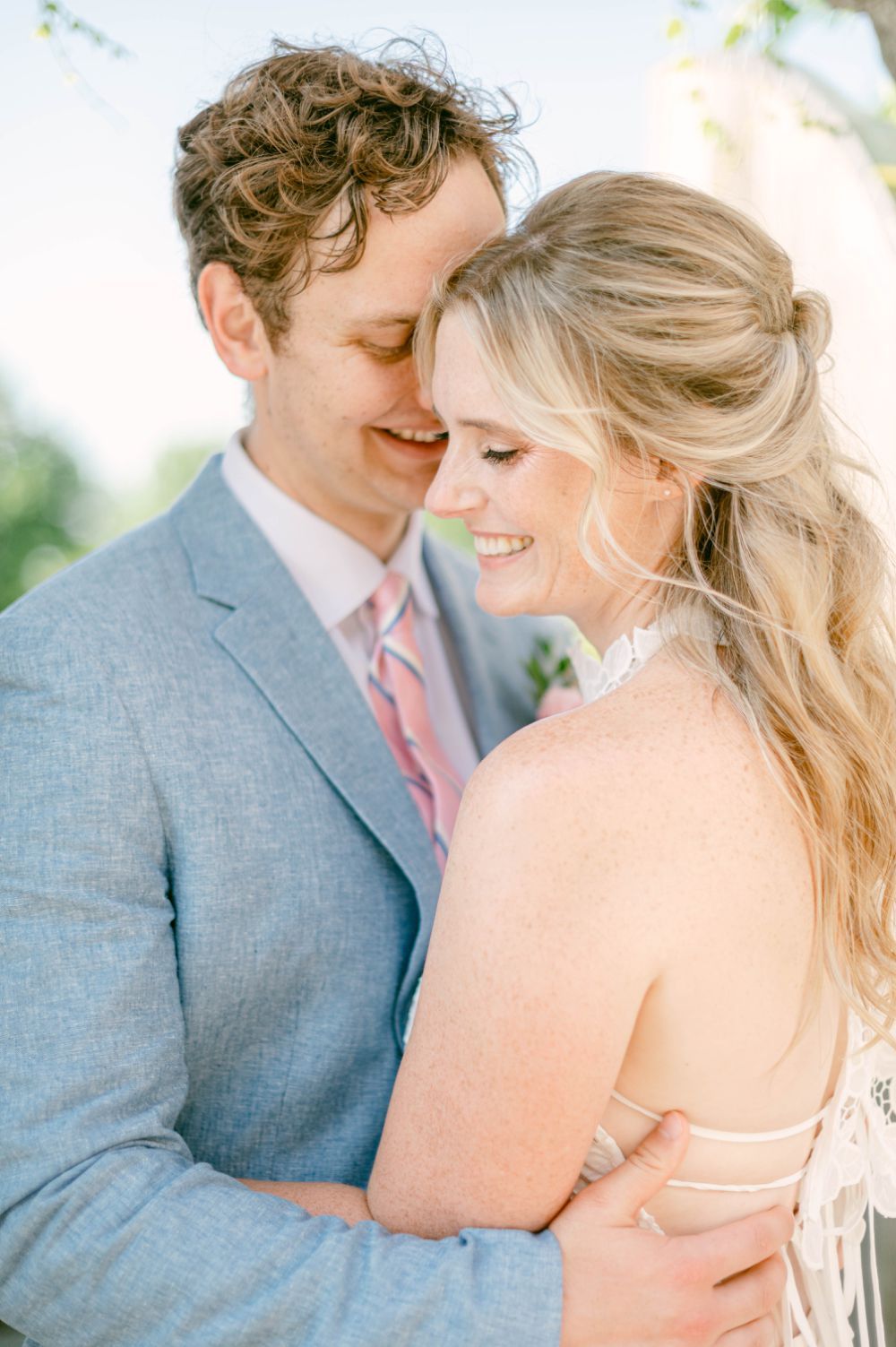 An intimate moment between newlyweds showing tender affection against a soft, bright background.