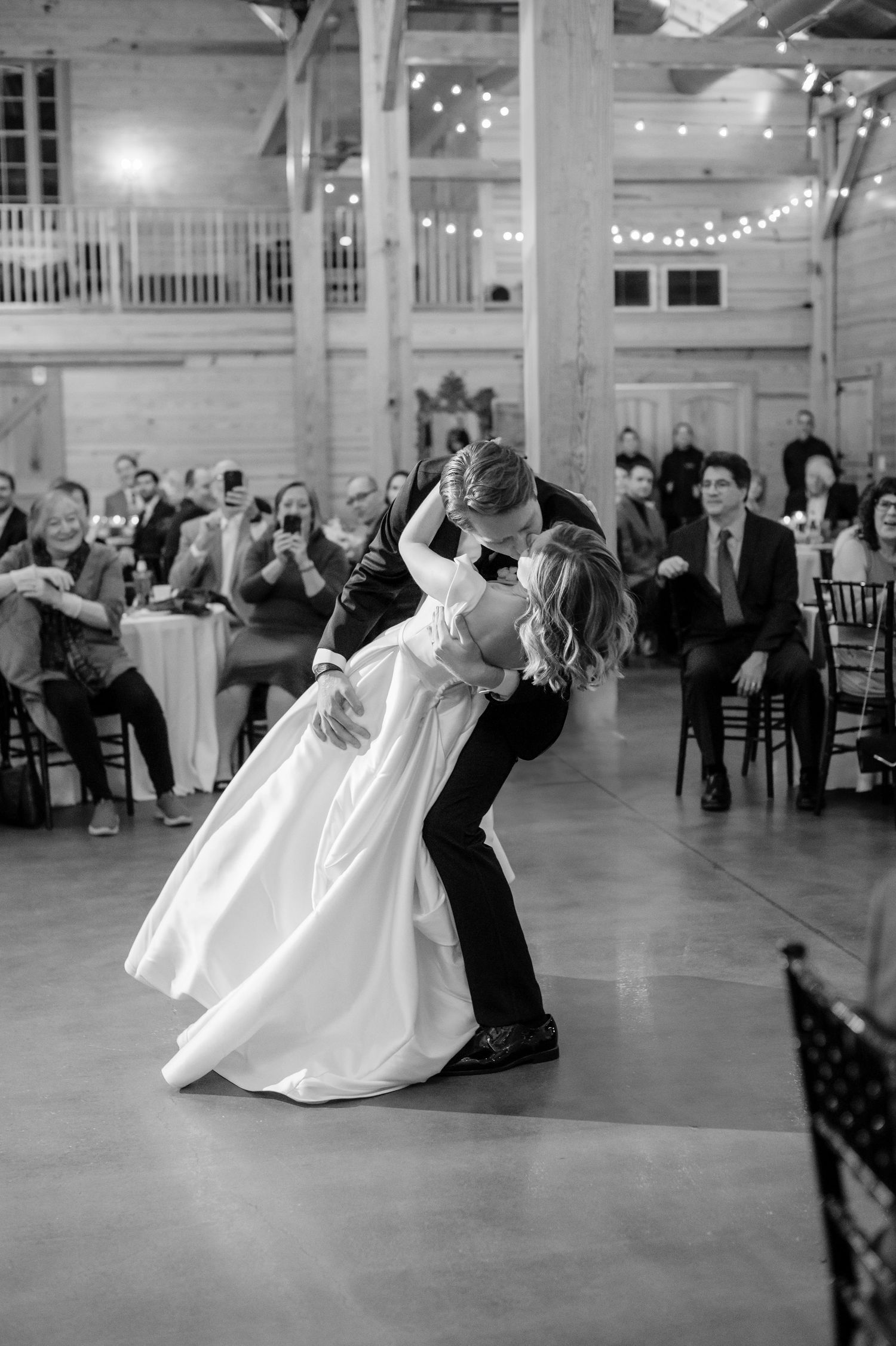 Black and white photo sequence shows a couple performing a dramatic dip dance move on a ballroom floor at a wedding reception.