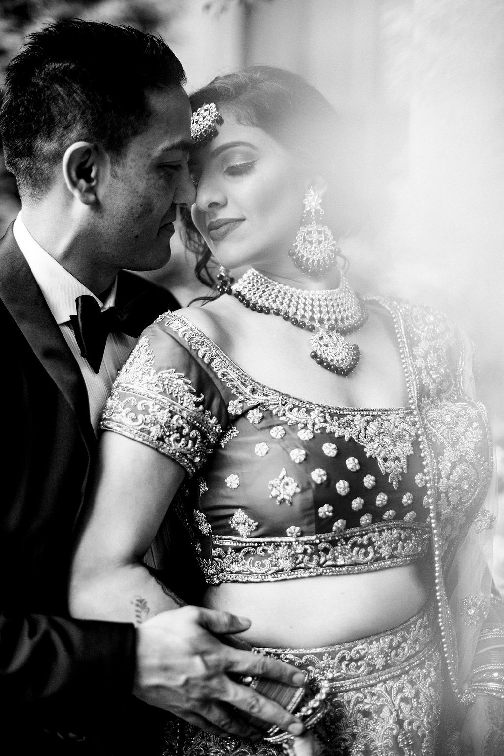 Romantic black and white photo series showing intimate moments between a couple in traditional Indian wedding attire.