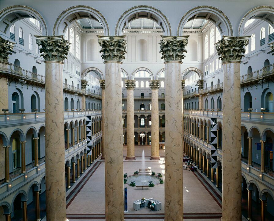 Interior view of the National Building Museum's Great Hall with towering Corinthian columns and multiple levels of arched galleries.