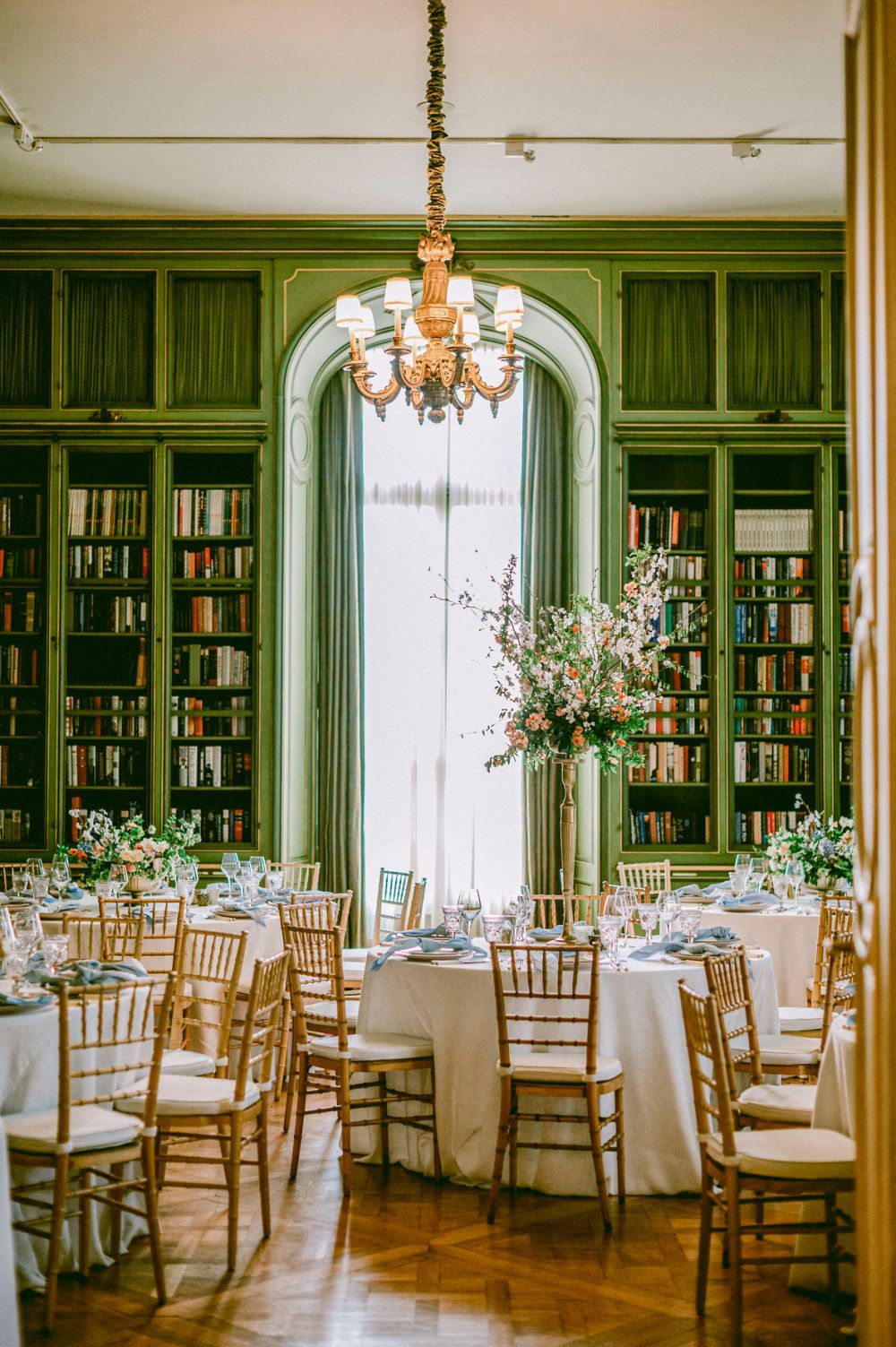 Elegant wedding reception venue Meridian House with green wood-paneled library walls, crystal chandeliers and tables set for dining.