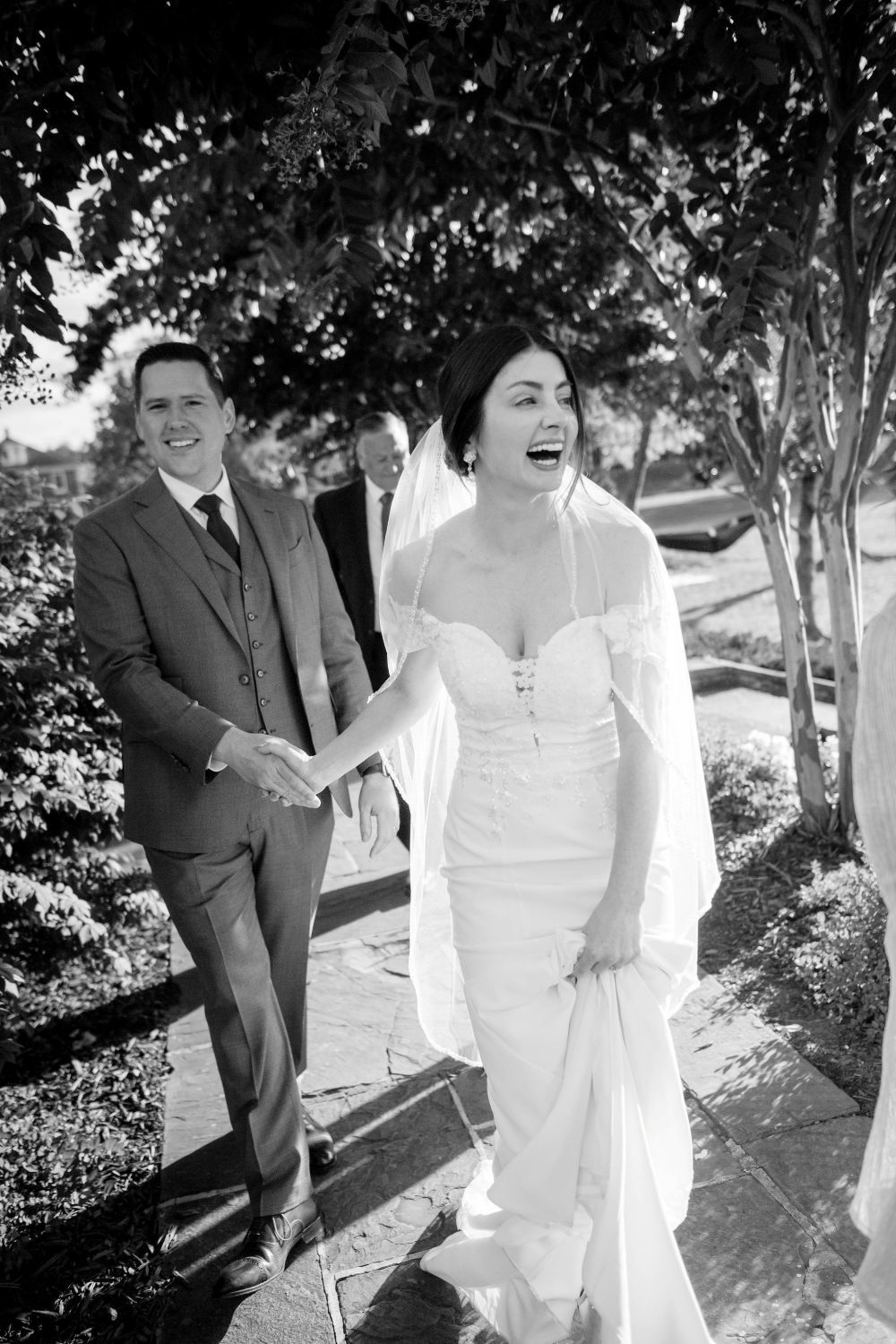A joyful black and white wedding photo series showing a couple walking and laughing together outdoors.