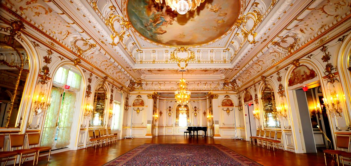 Ornate baroque palace interior with gilded moldings, crystal chandeliers and painted ceiling in a grand gallery hall.