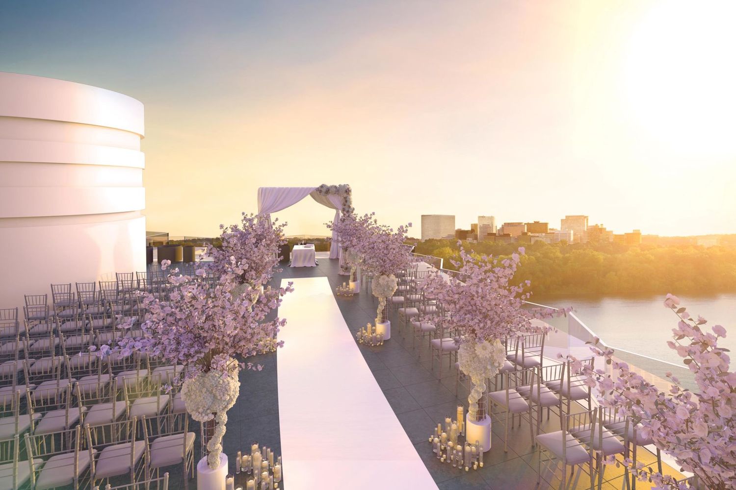 A scenic wedding ceremony setup on a rooftop terrace with white chairs and floral decorations at sunset.