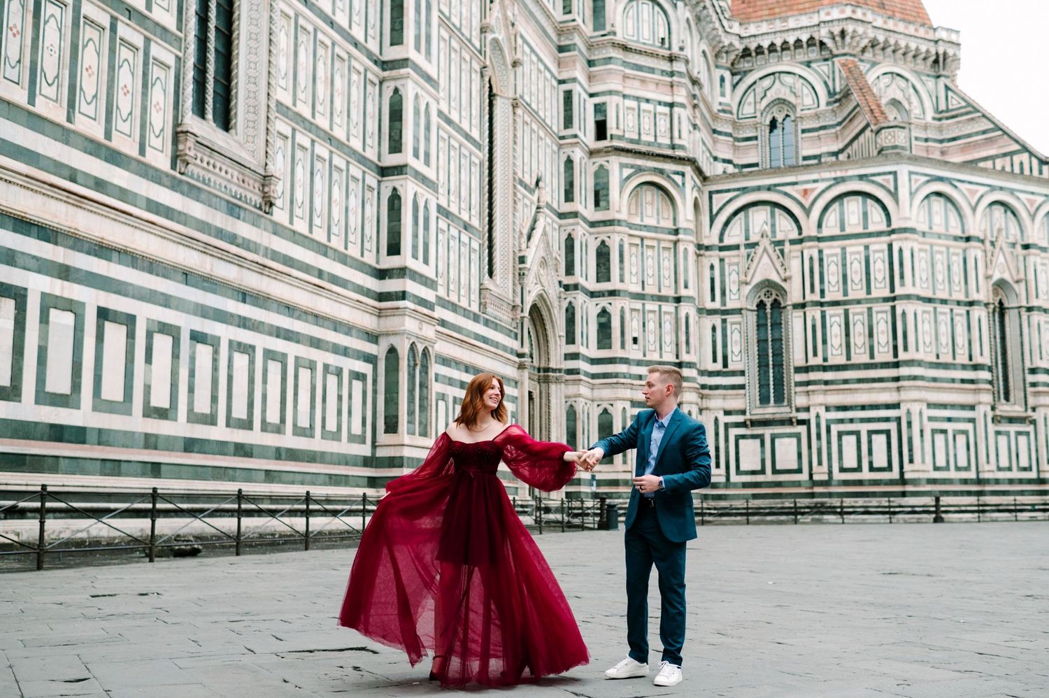 A couple dances in front of the ornate marble facade of Florence's Duomo cathedral in Italy.