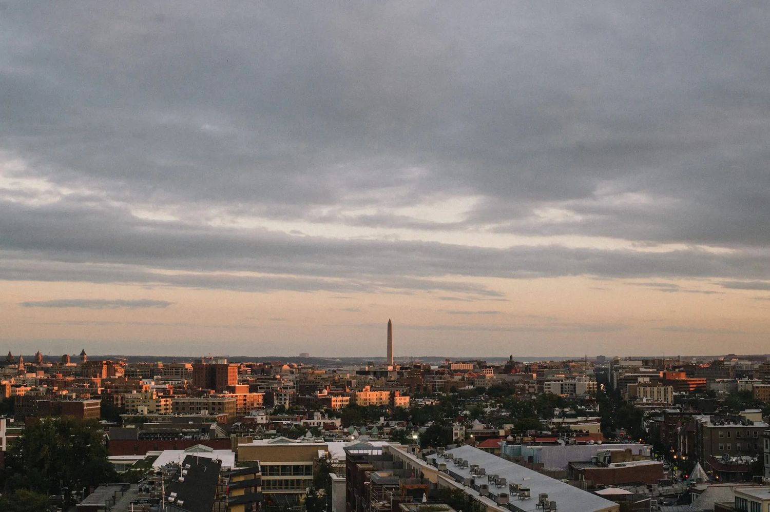 Aerial cityscape view from the Line Hotel in Washington DC at sunset with dramatic cloudy sky and urban buildings stretching to the horizon.