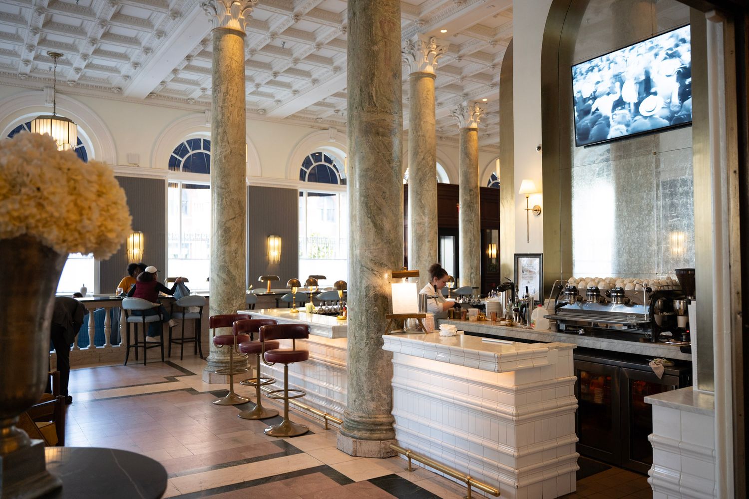 Interior view of a luxury hotel lobby with ornate white columns, marble floors, and elegant seating areas.