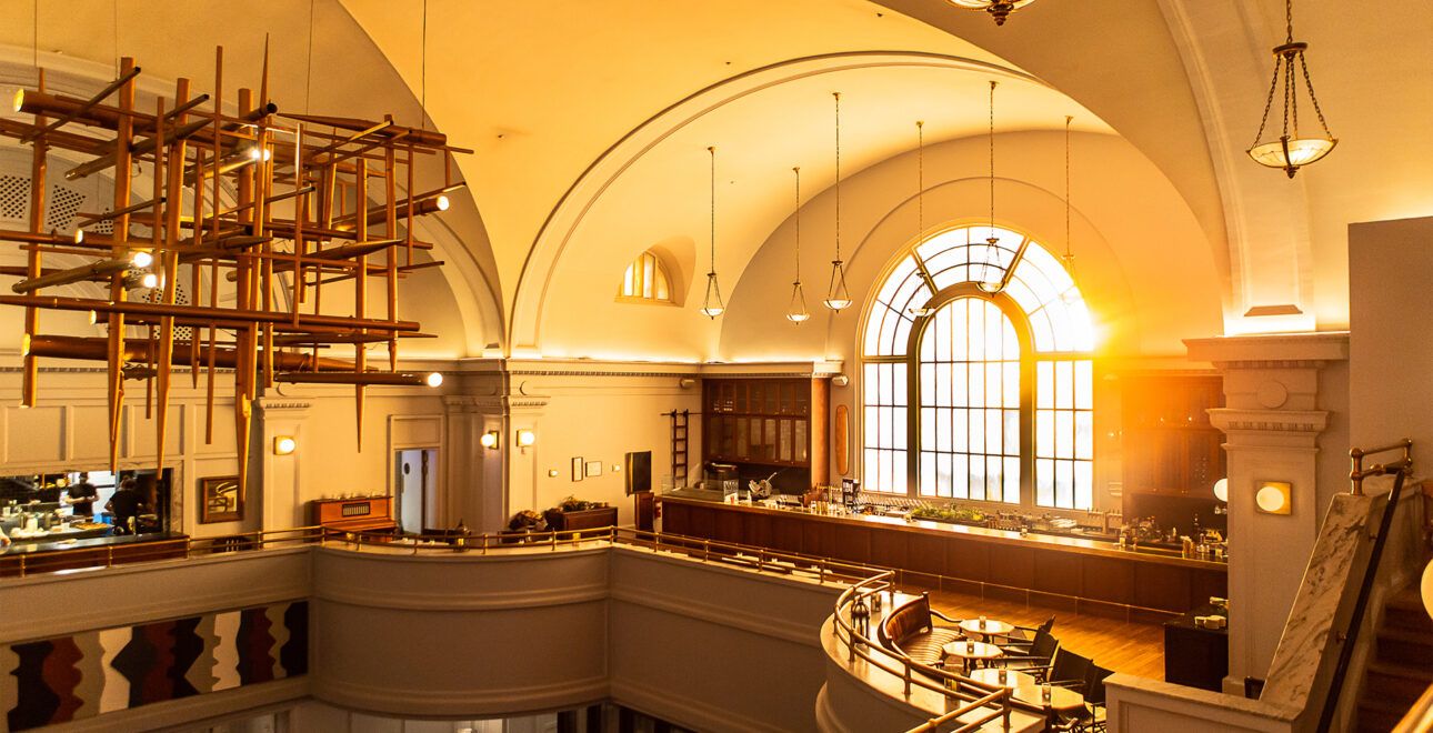 Panoramic view of an elegant library interior with arched windows, wooden shelves and warm lighting creating a cozy atmosphere.