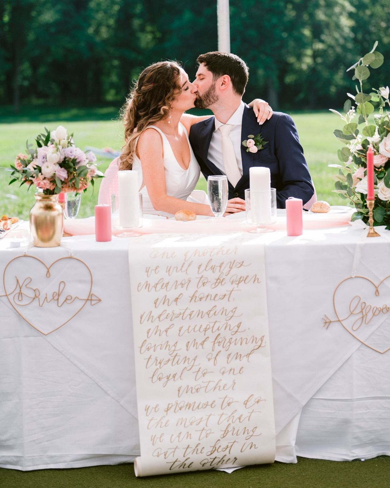 A romantic couple shares an intimate moment at an outdoor wedding reception with calligraphy signs on the table at wedding venue Antrim 1844