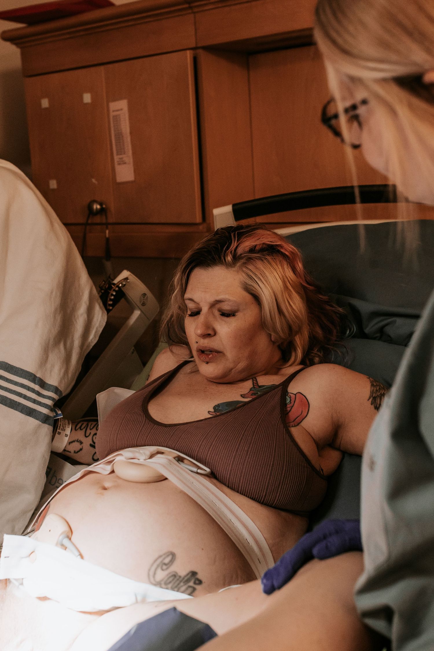 Pregnant woman in hospital bed during labor, attended by medical staff in a delivery room setting.