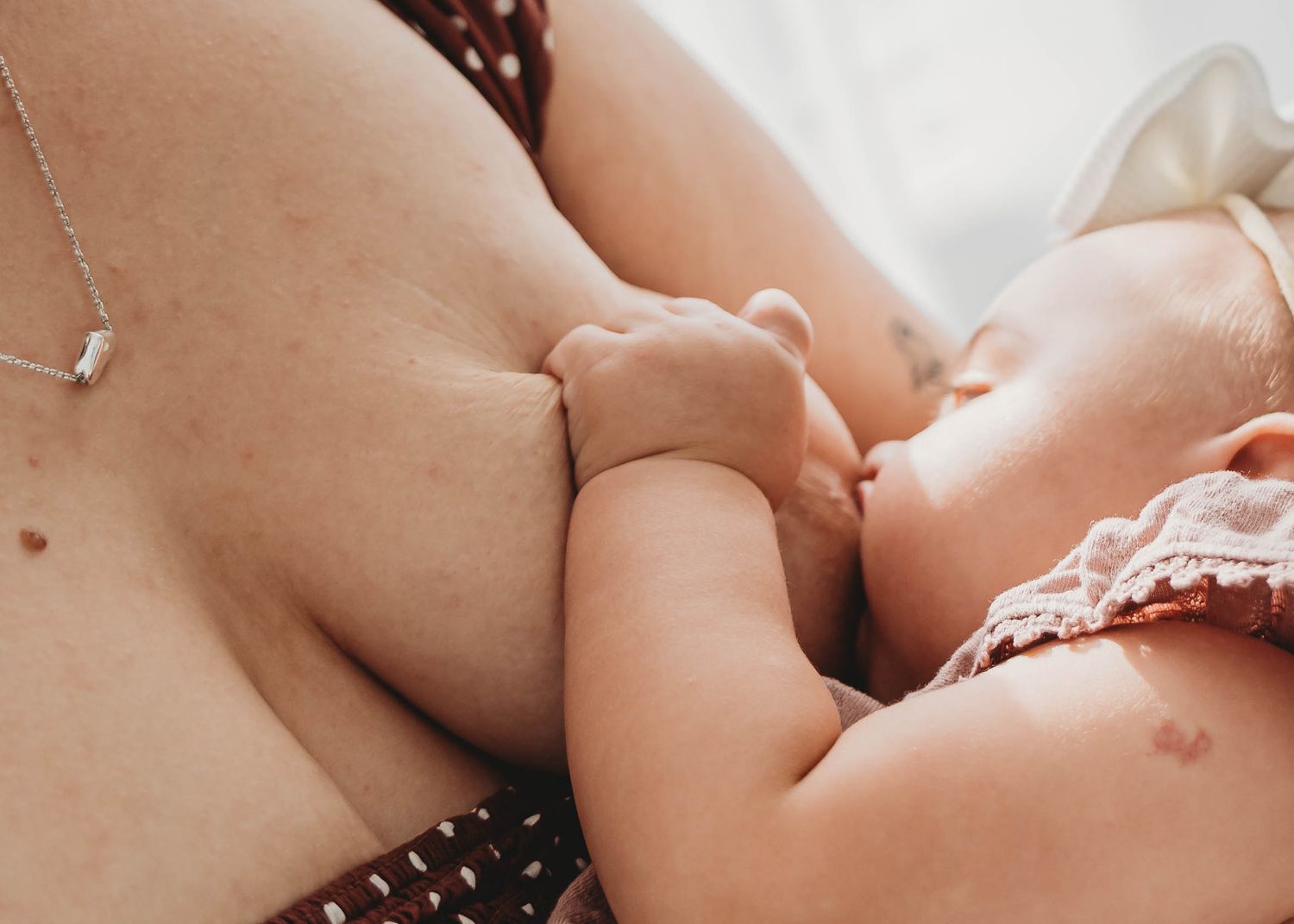 Close-up of newborn baby breastfeeding during an intimate lifestyle newborn photography session at home.