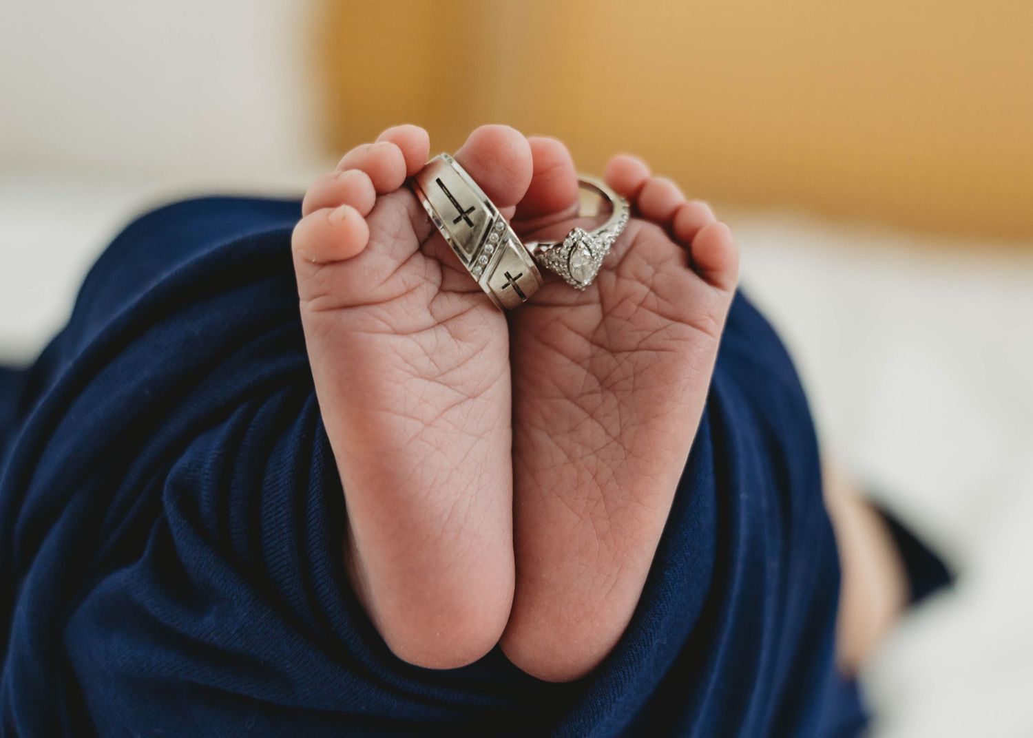 Two wedding rings placed on soles of newborn baby's tiny feet.