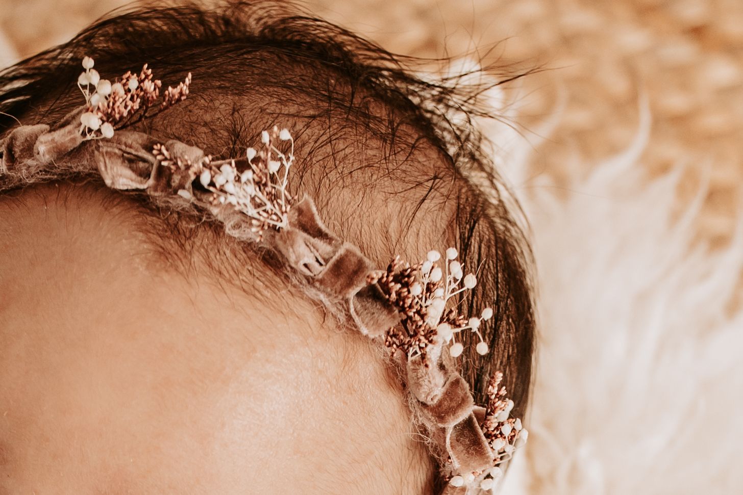 Detail shot taken by Keely King Photography of a newborn girls hair with a purple headband on with bows and flowers in Broken Arrow Oklahoma