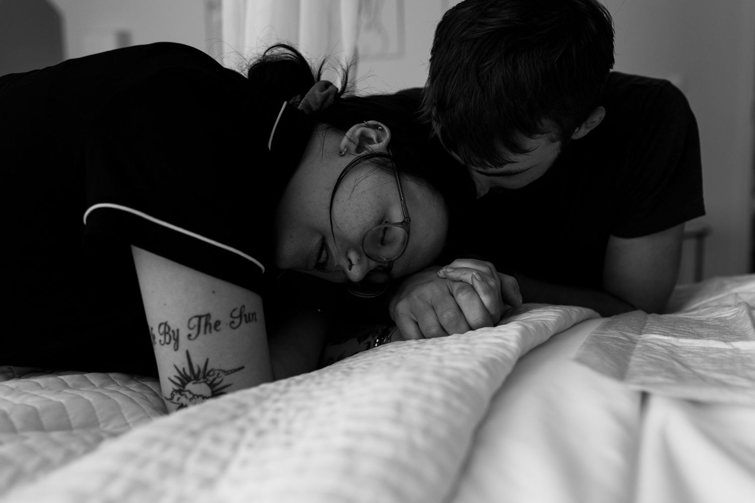 Couple sharing emotional moment together on bed in black and white while she is in labor.