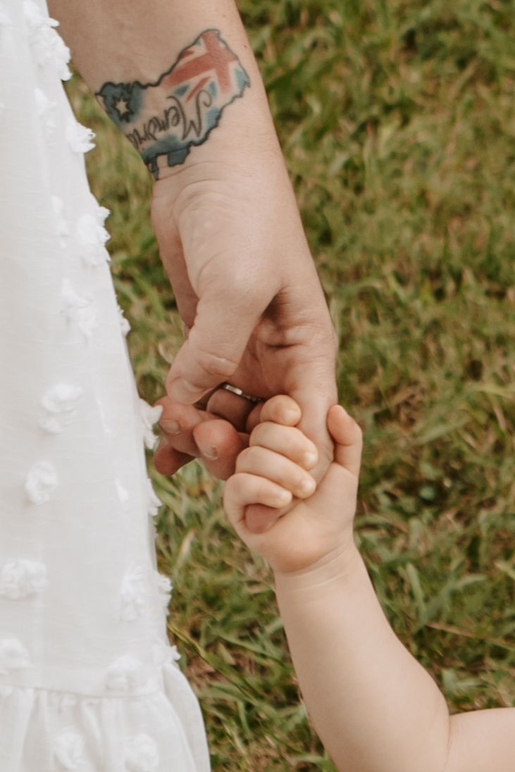 close up of a baby holding her mother's finger while walking through Coal Creek Farm with Keely King Photography in Jenks Oklahoma