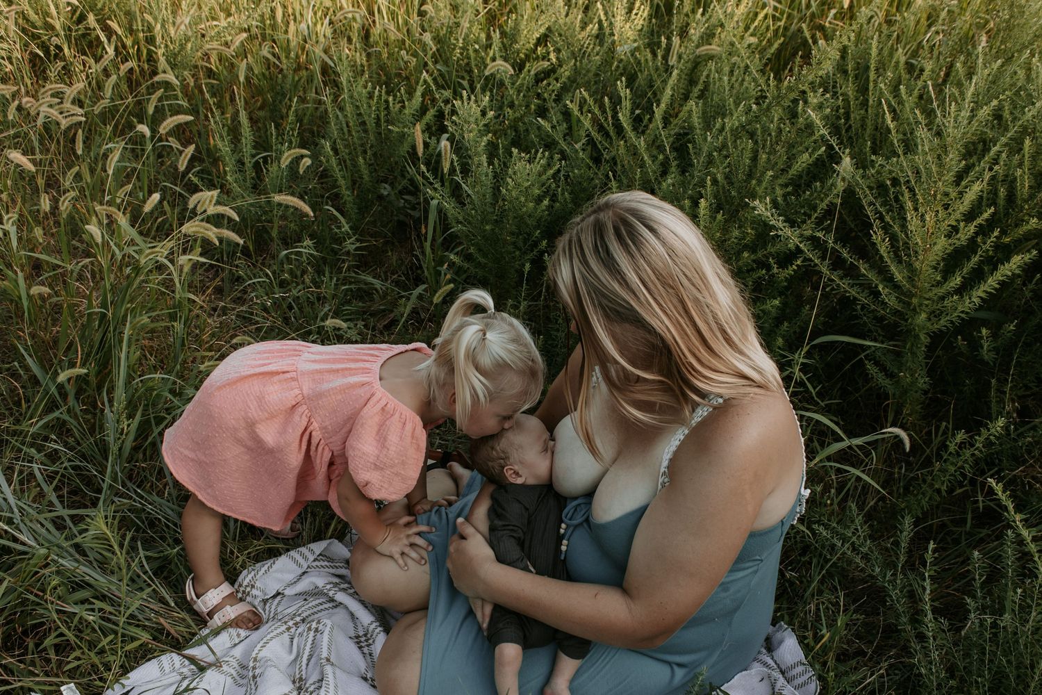 Keely King Photography captures toddler girl kiss newborn sibling while he is breastfeeding during a family session in Claremore, Oklahoma.
