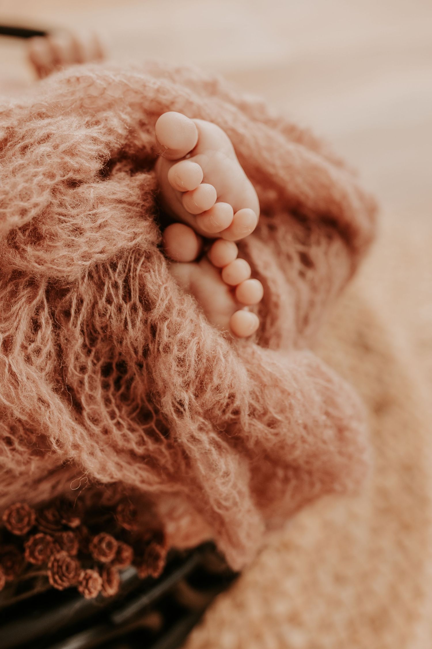Tiny newborn baby feet peeking out from a soft pink fuzzy knit blanket in a wicker basket taken by Keely King Photography in Coweta Oklahoma