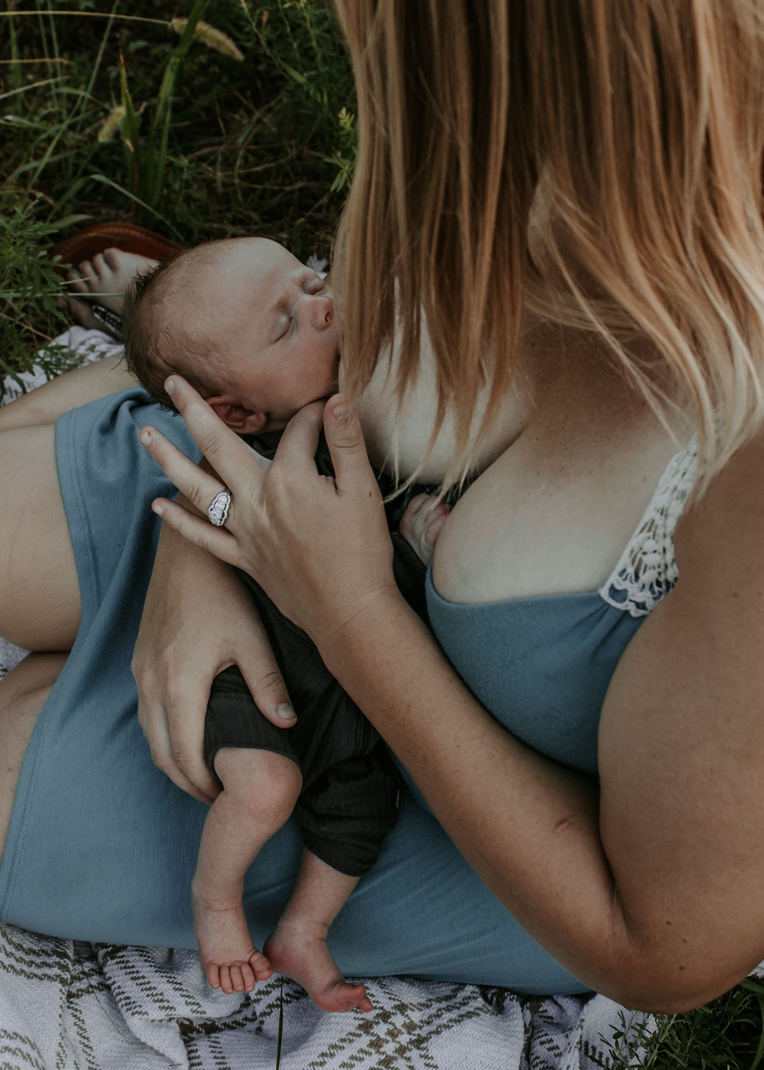 Close up of mother curressing newborn baby's face with breastfeeding. Keely King Photography family session during golden hour in Claremore