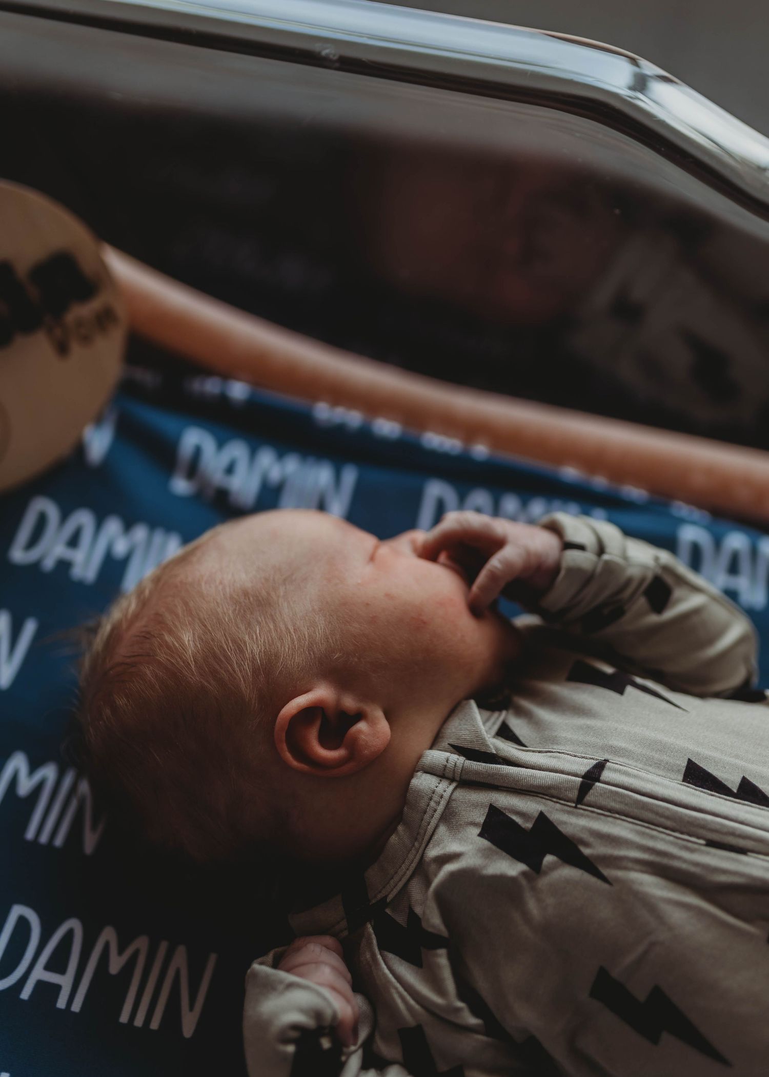 Newborn baby lying on a personalized blue blanket with the name Damin printed on it.