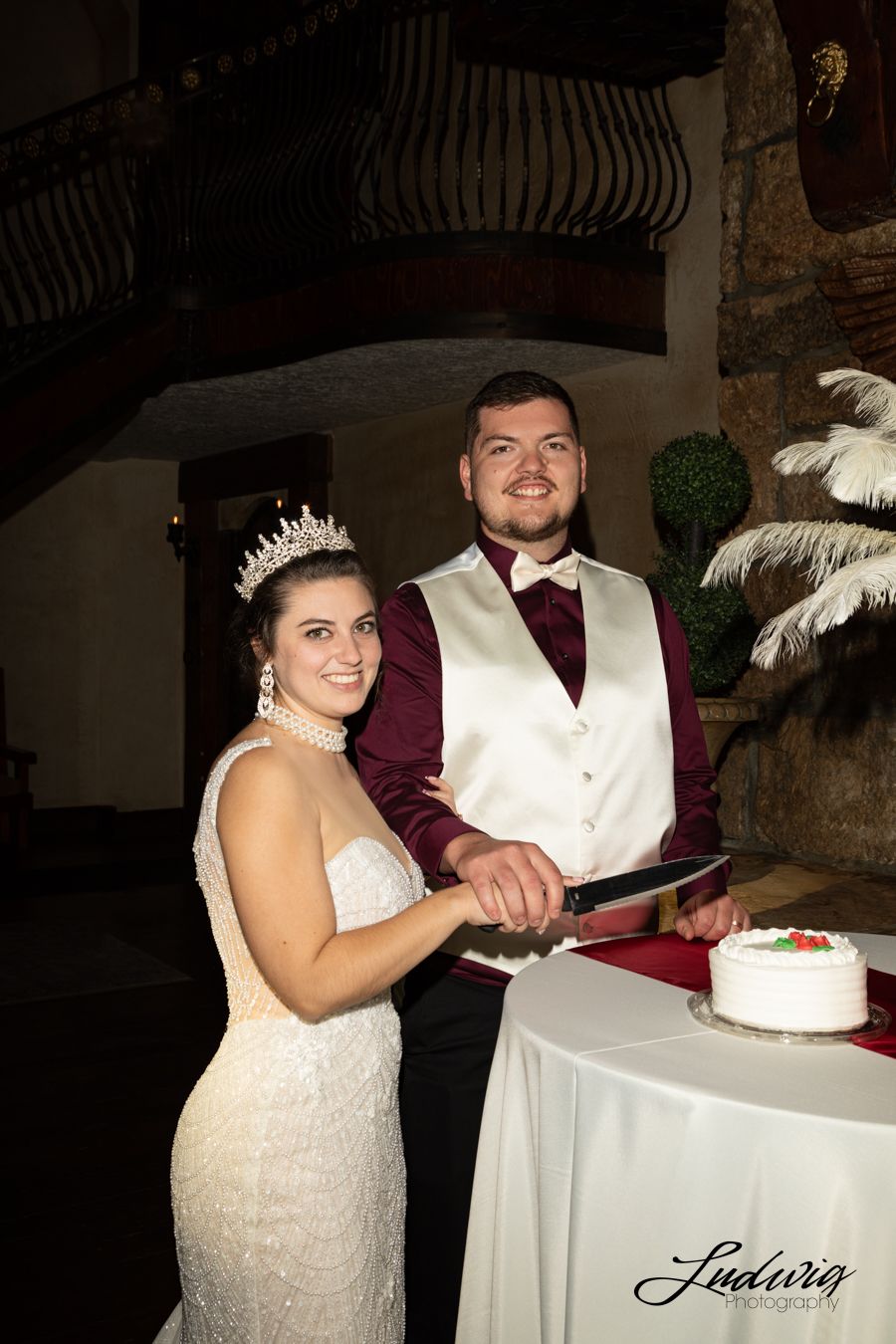 Couple cuts a Walmart cake inside castle at Wadley Farms Lindon, Utah. The bride is wearing a Wona bridal gown with pearls and lace.
