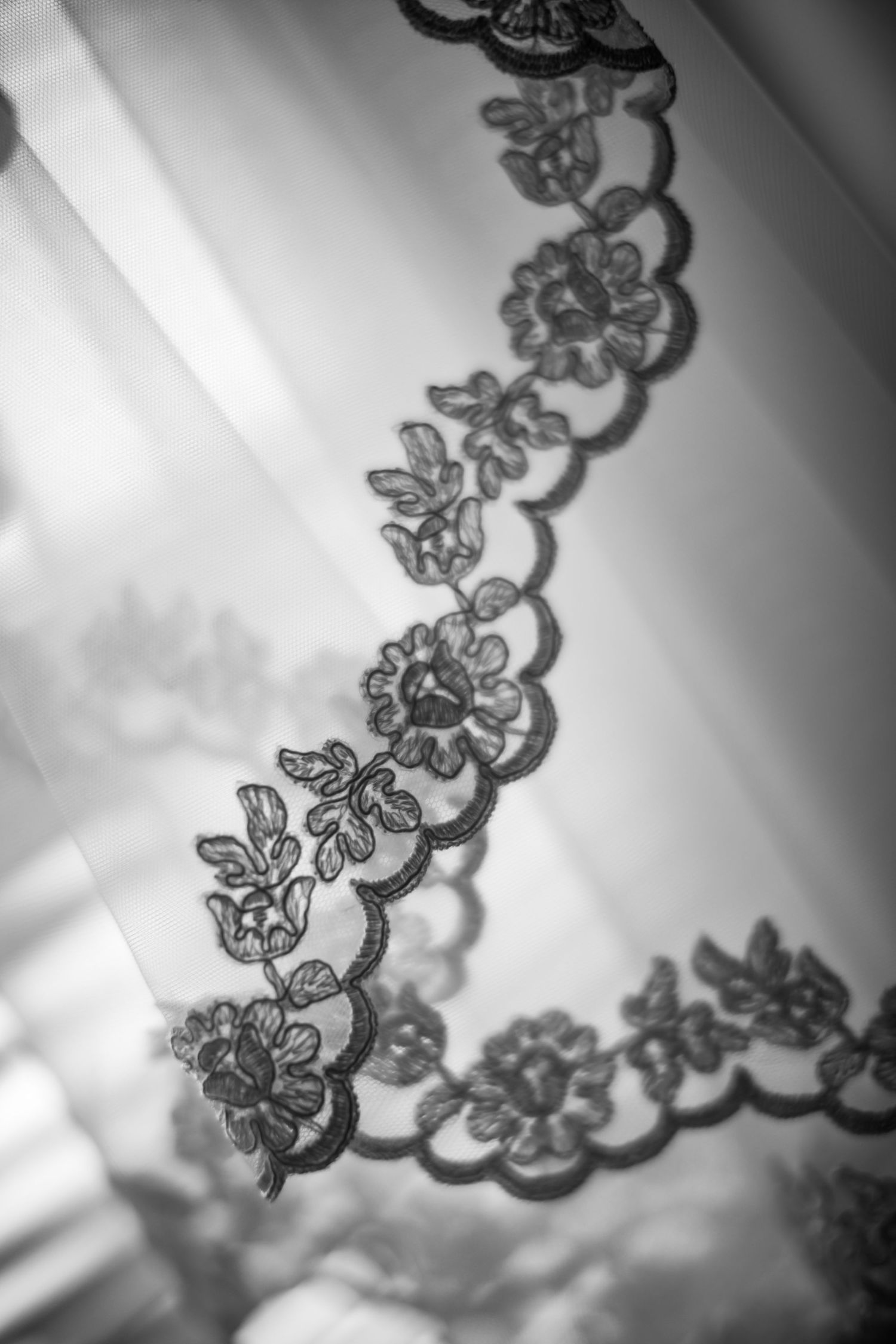Close-up of the floral lace trim on a bride's wedding dress veil in black and white.