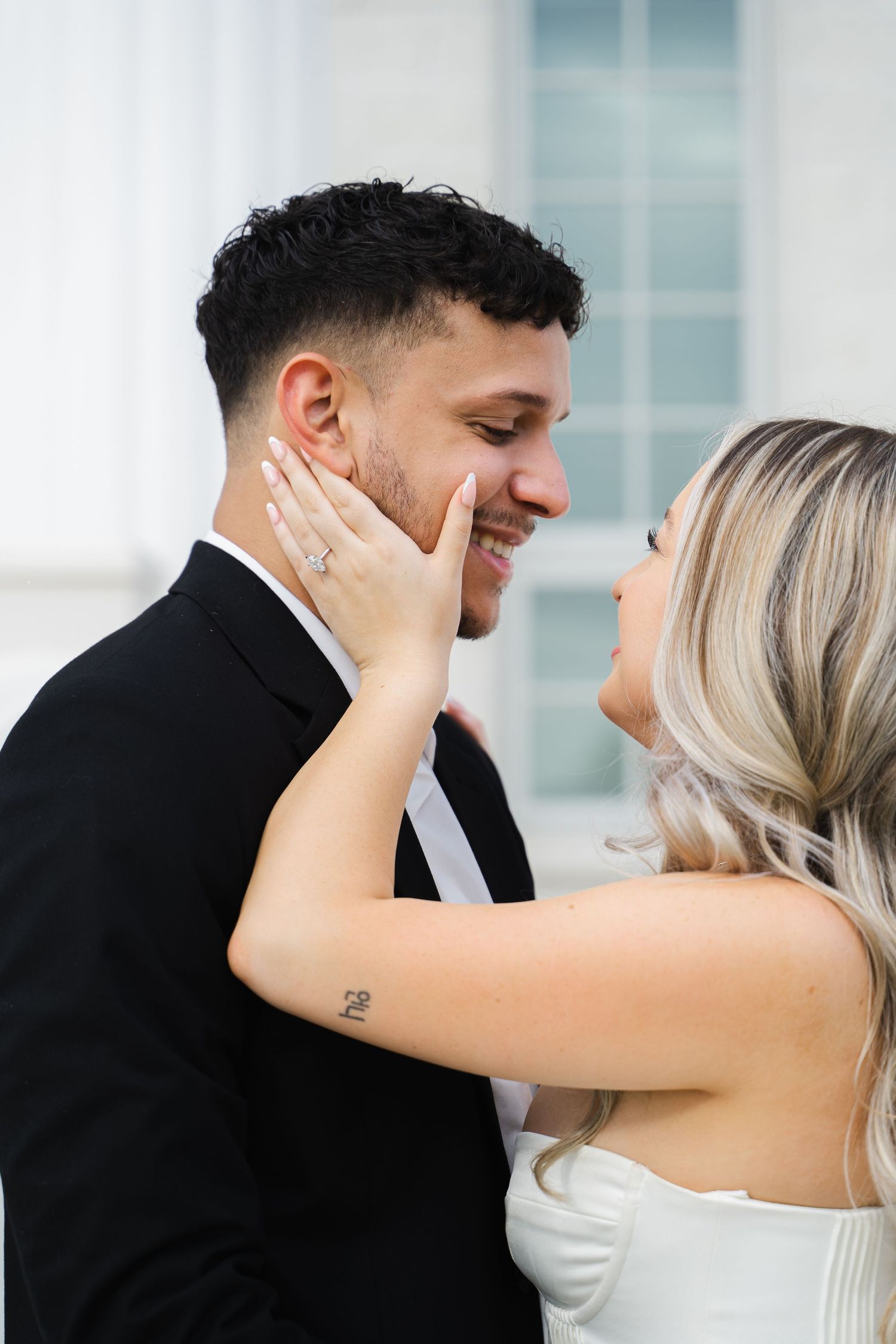 Happy couple sharing romantic moment, bride with engagement ring gently cupping grooms smiling face.