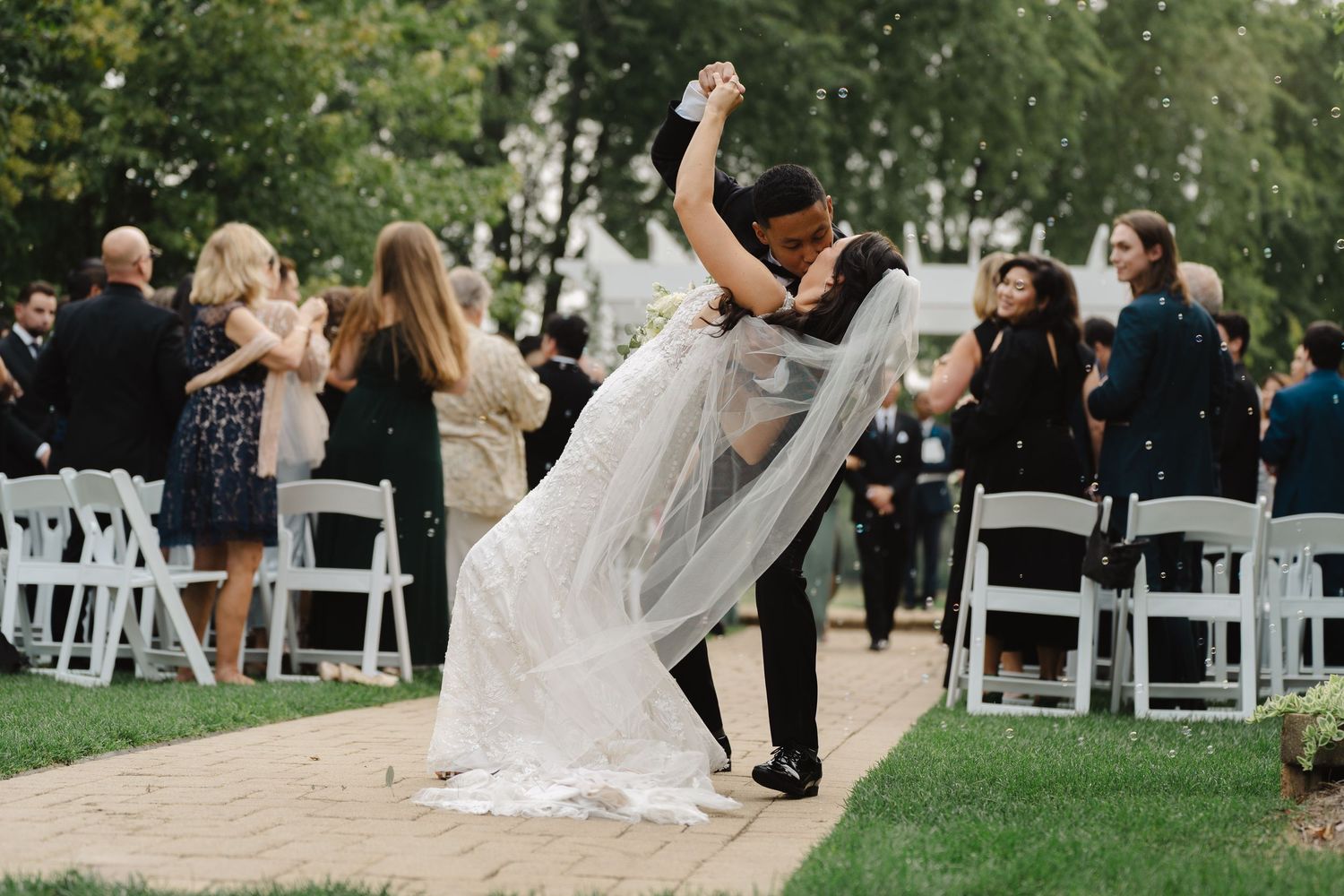 Groom dipping bride dramatically at the altar after outdoor wedding ceremony.