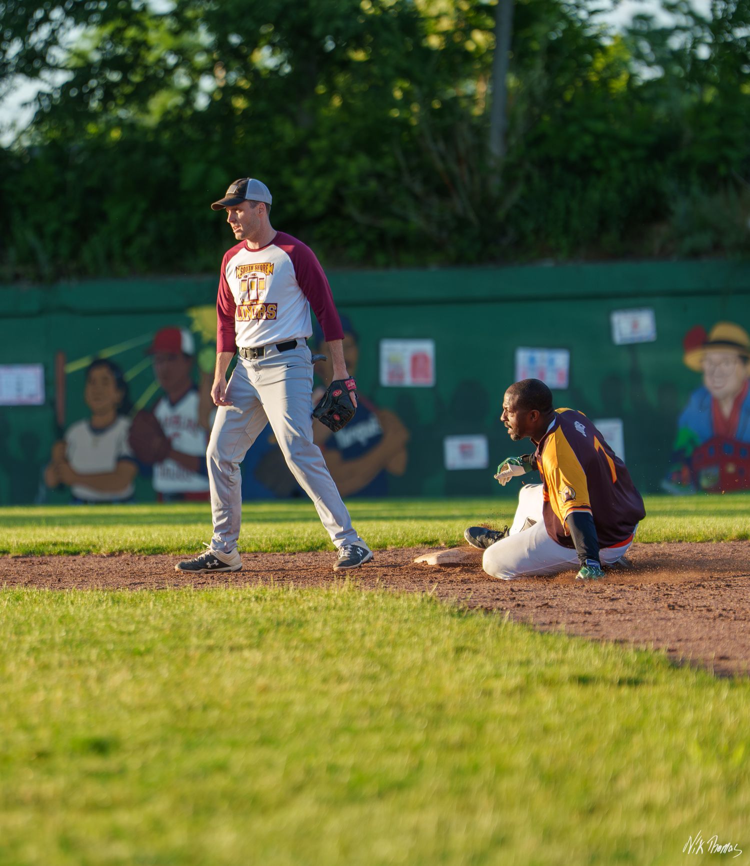 A baseball player slides into base as the infielder with a glove stands over him during a game.