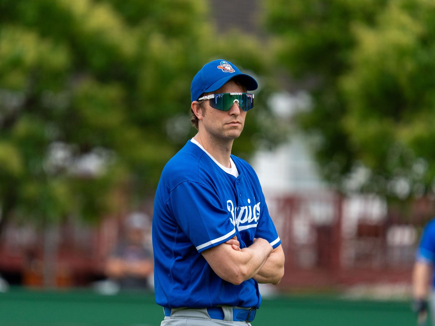 Baseball player in blue Rapids jersey and sunglasses standing with arms crossed.