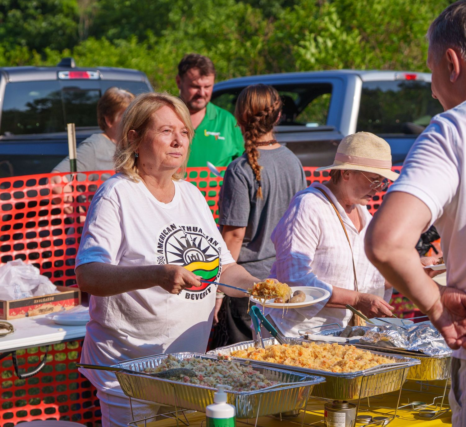 Volunteers serving food at an outdoor community cultural festival buffet table.