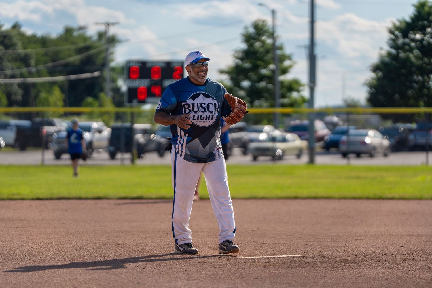 Baseball player in Busch Light jersey stands ready on field during a sunny outdoor game.