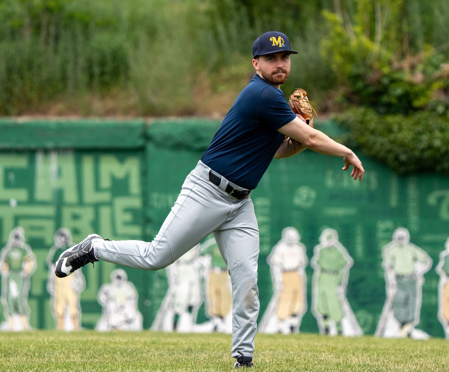 Baseball player in Michigan Wolverines uniform fielding a ball during an outdoor practice session.