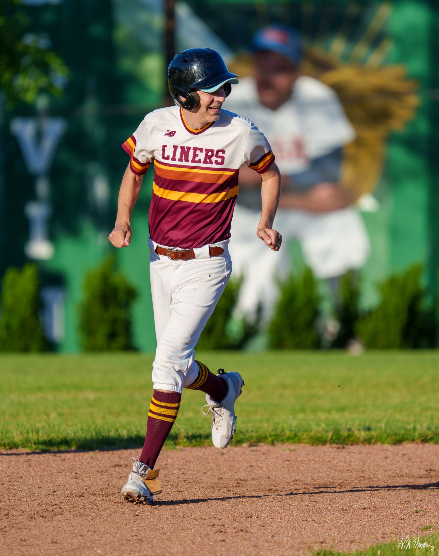 Baseball player in Liners uniform running bases during a sunny outdoor game.